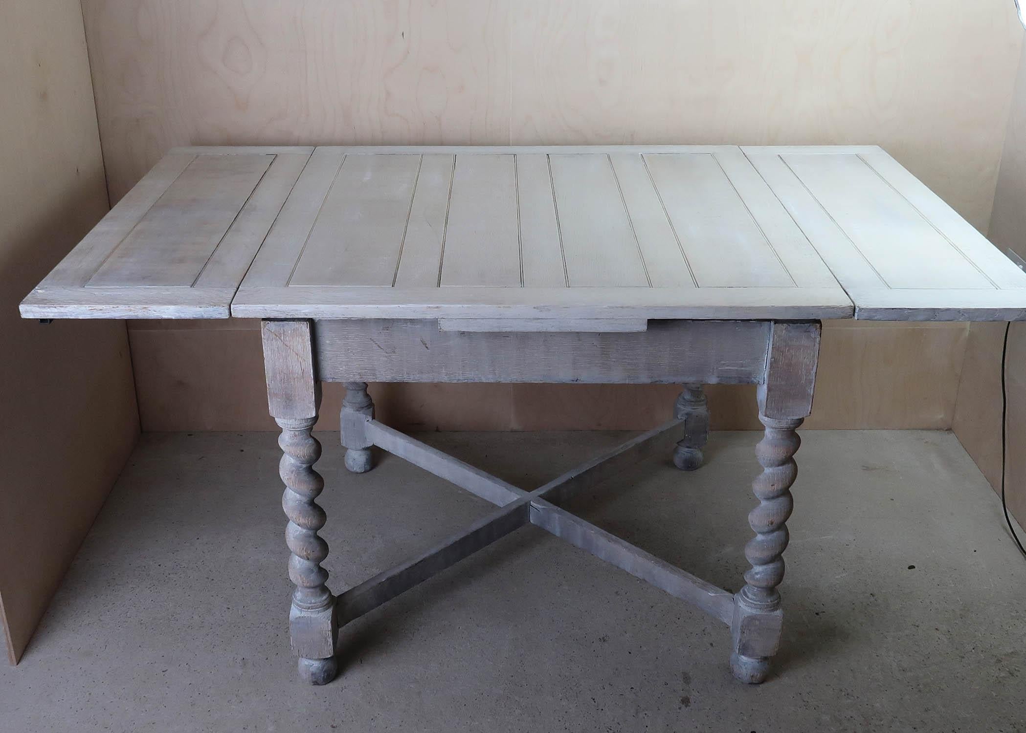 A lovely limed oak dining or kitchen table with barley twist supports.

It is a draw leaf table so it gives you the option of having the leaves pushed under the top to make a smaller square table.

The measurement below is the maximum. Without