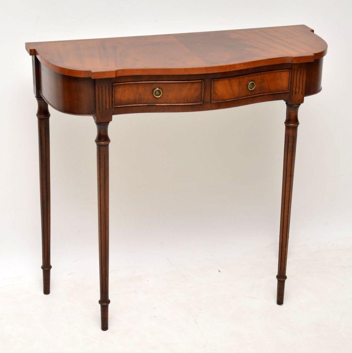 Small antique mahogany serpentine shaped console table in lovely condition and dating from around the 1950s period. It has a flame mahogany cross banded top, two drawers and turned fluted legs. These kind of side tables that are slim from back to