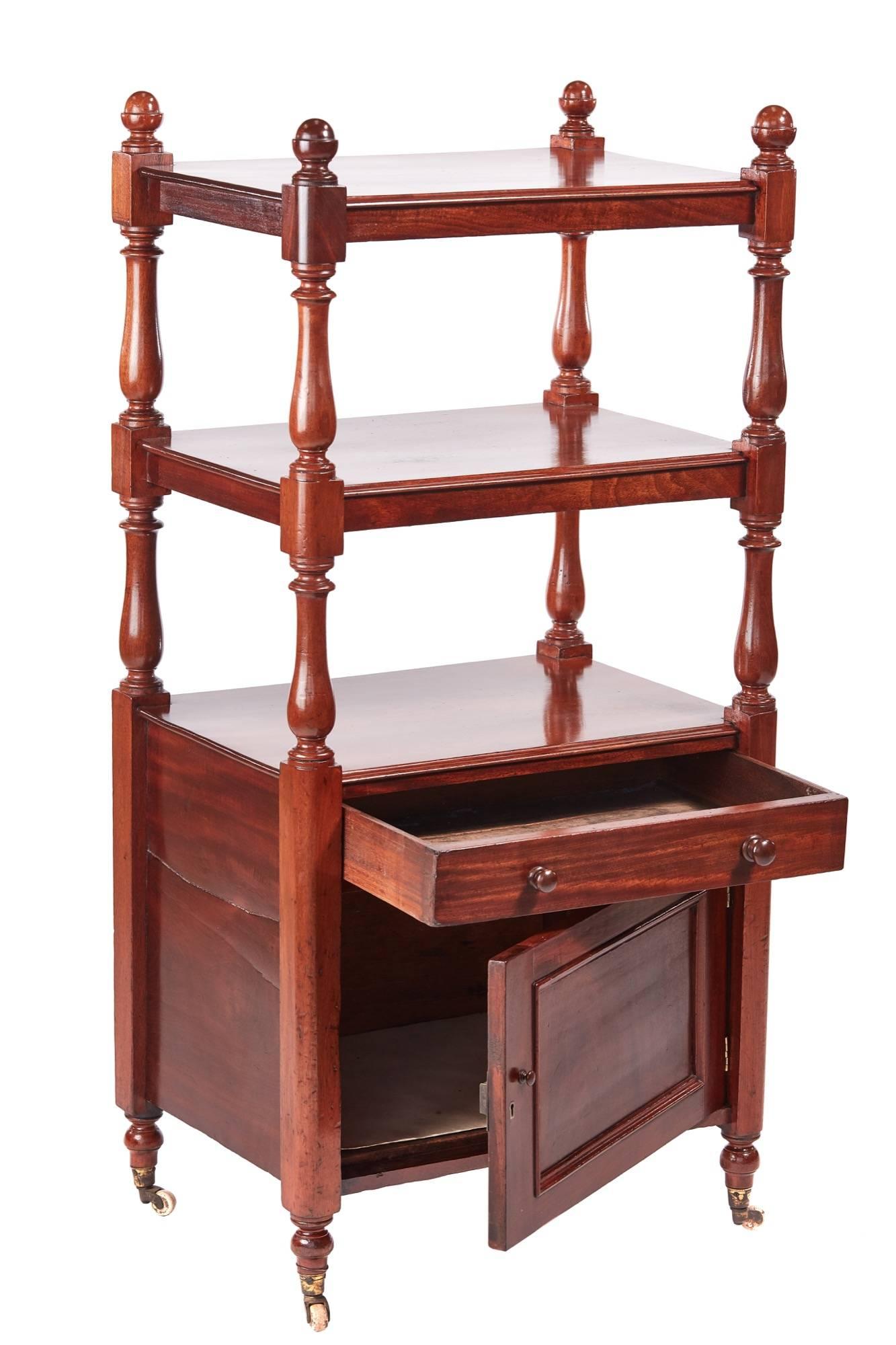 Small antique mahogany dumb waiter, with two mahogany tiers supported by shaped turned columns, one long drawer with original turned knobs, one cupboard door, standing on short turned legs with original castors.
