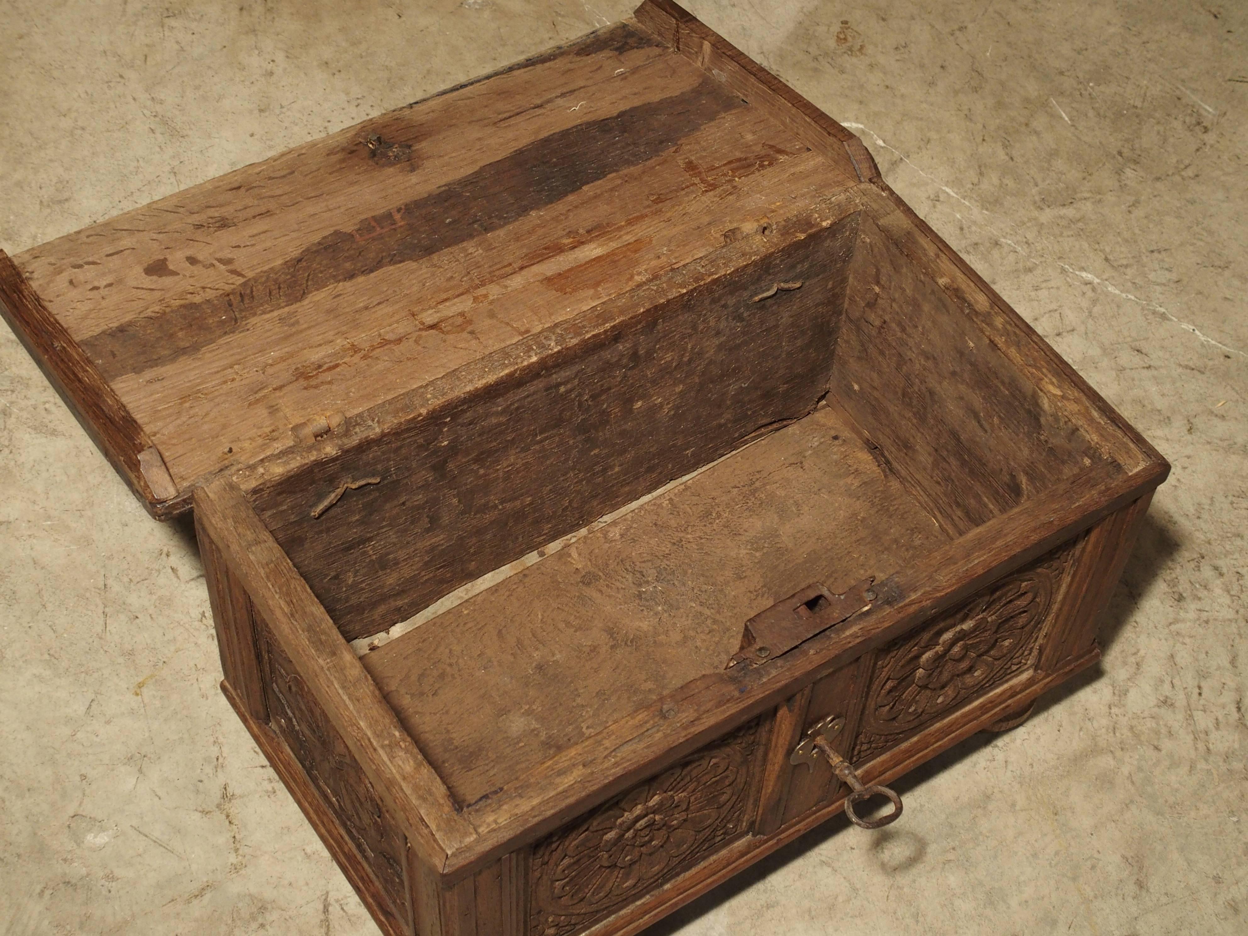 This antique oak table trunk is from Spain and dates to the 1600s. The top is attached to the back panel with two wrought iron hinges with decorative straps that cover most of the top. It is interesting to note that there are slightly different