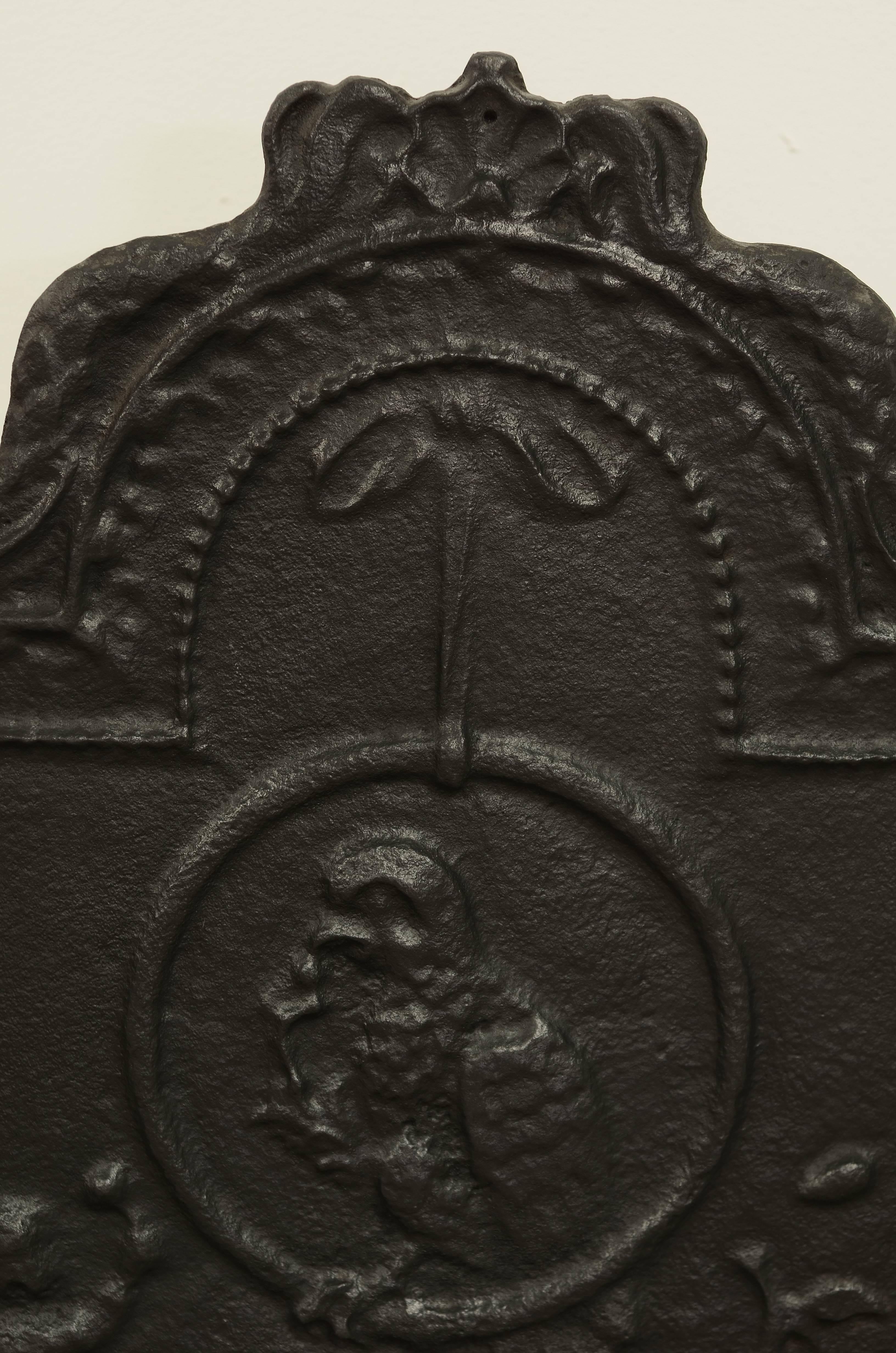 Lovely decorative antique cast iron fireback showing a parrot sitting in a ring.

Excellent condition, can be used in an real fireplace or as a very decorative backsplash.
Can be supplied with stand.