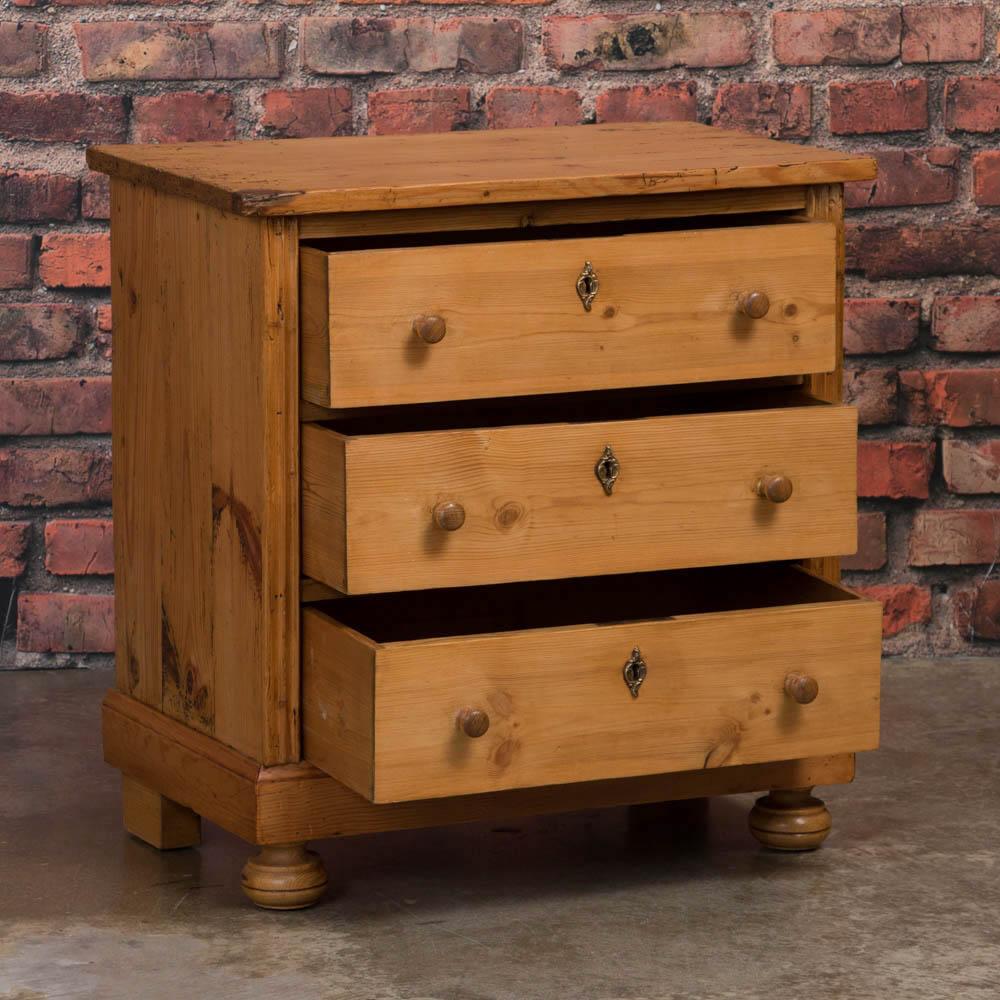 This small antique pine chest of drawers from Denmark features three drawers resting on bun feet. A charming country piece - simple and clean - perfect as a nightstand.