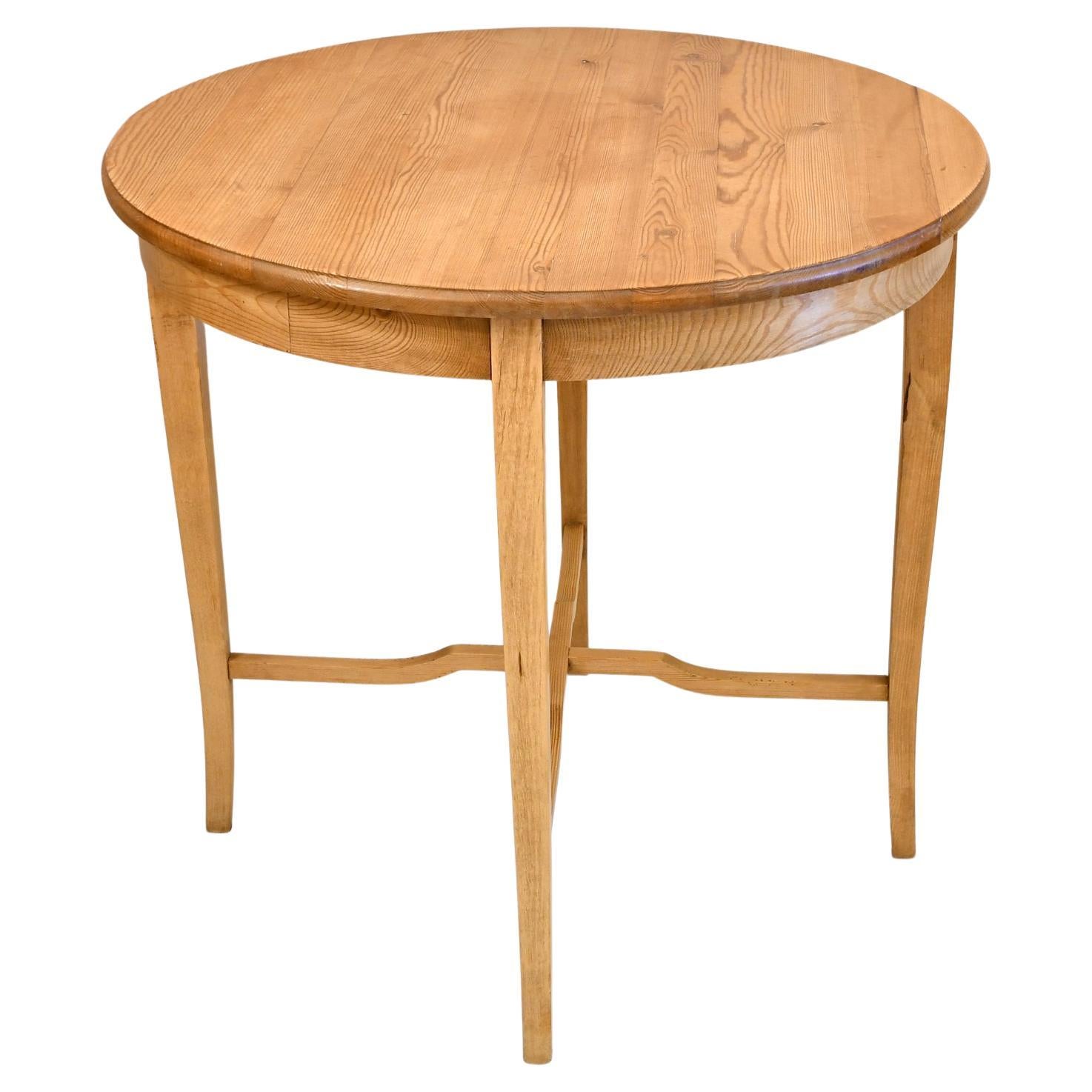 A very well-crafted antique European pine end table with round top over four square tapered legs that slightly curve & are joined by an 