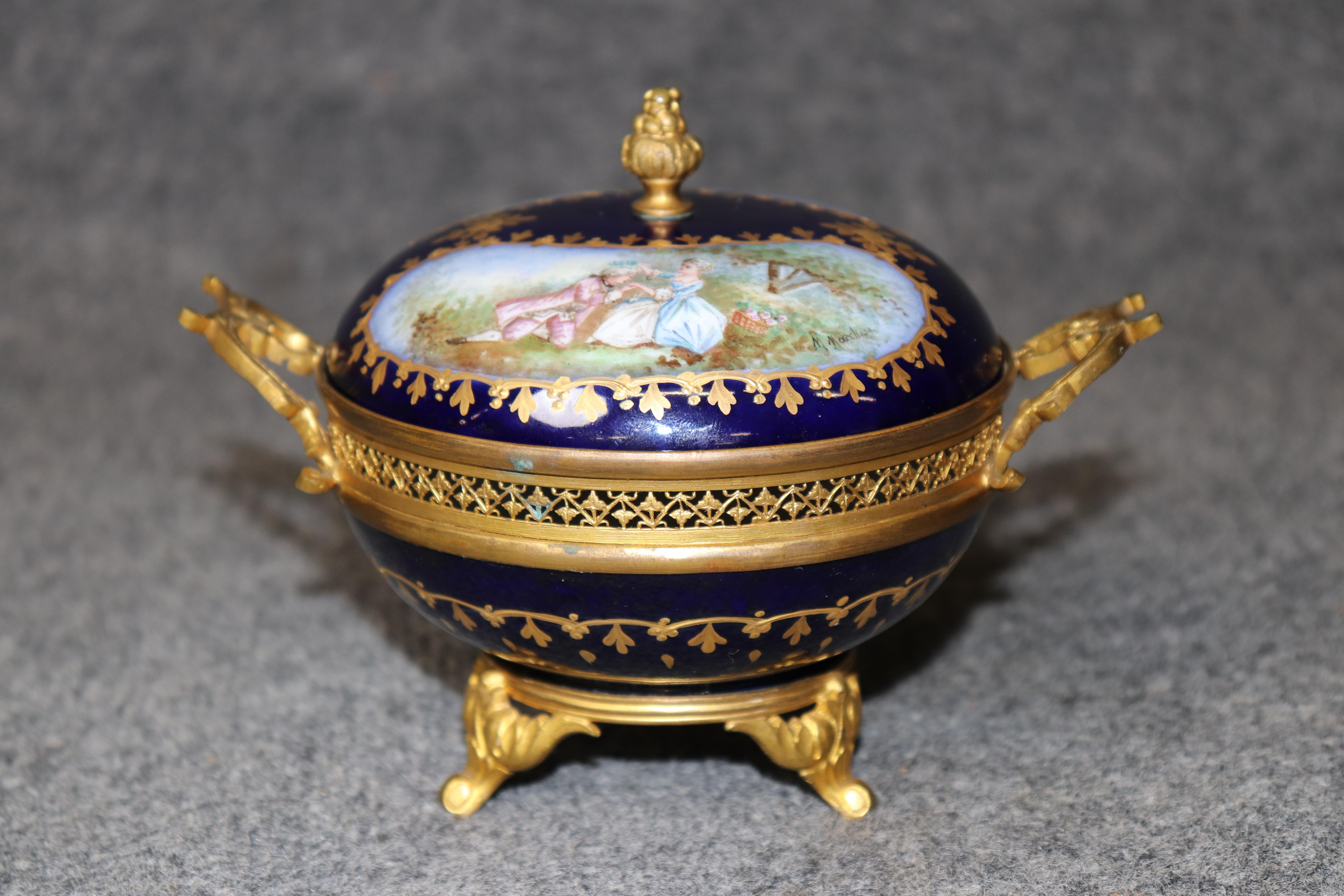 Dimensions - H : 5 1/4 in W : 6 3/4 in D : 5 in 

Cette exquise petite urne ancienne en porcelaine de Sèvres est un exemple stupéfiant de l'art et de l'élégance français du 19e au début du 20e siècle. Finement réalisée en porcelaine bleu cobalt,