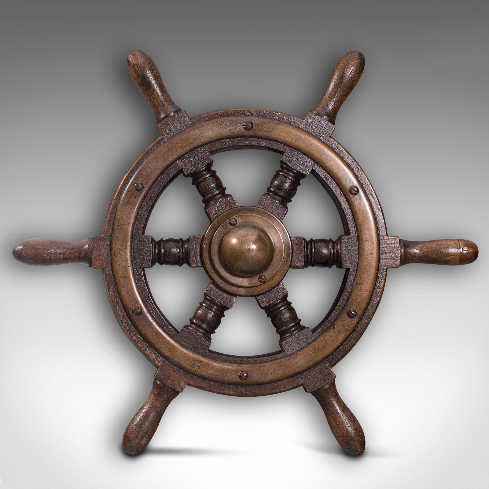 This is a small antique ship's wheel. An English, teak and bronze maritime decorative helm, dating to the early 20th century, circa 1920

Delightful example with maritime appeal
Displays a desirable aged patina throughout
Solid teak shows fine