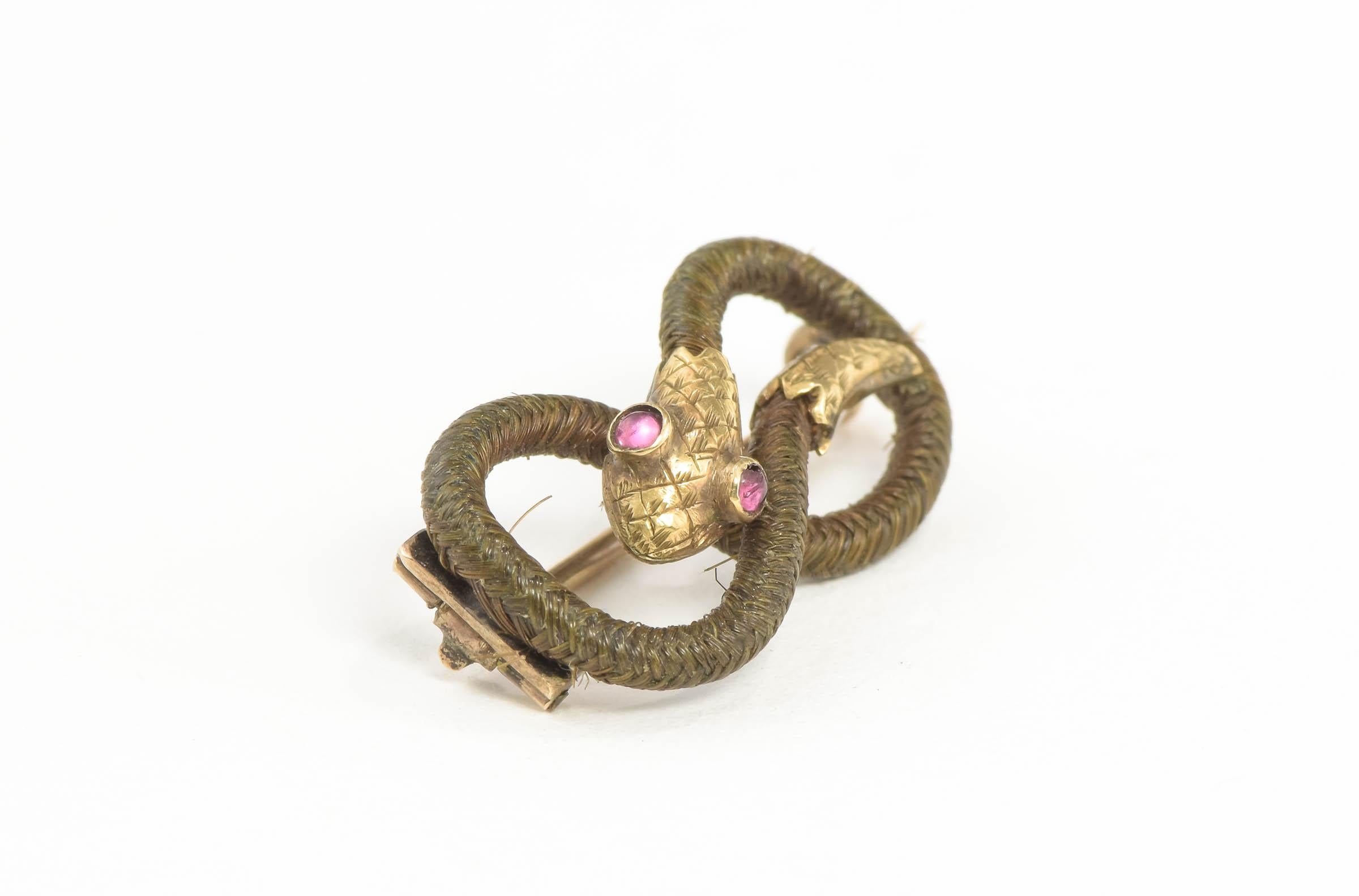Crafted of gold testing at a minimum of 9K - 10K and hairwork, the brooch pin features a sinuously designed snake in a sentimental eternity knot design. All original, the snake's head and tail are lovingly detailed. This could be a memorial/mourning
