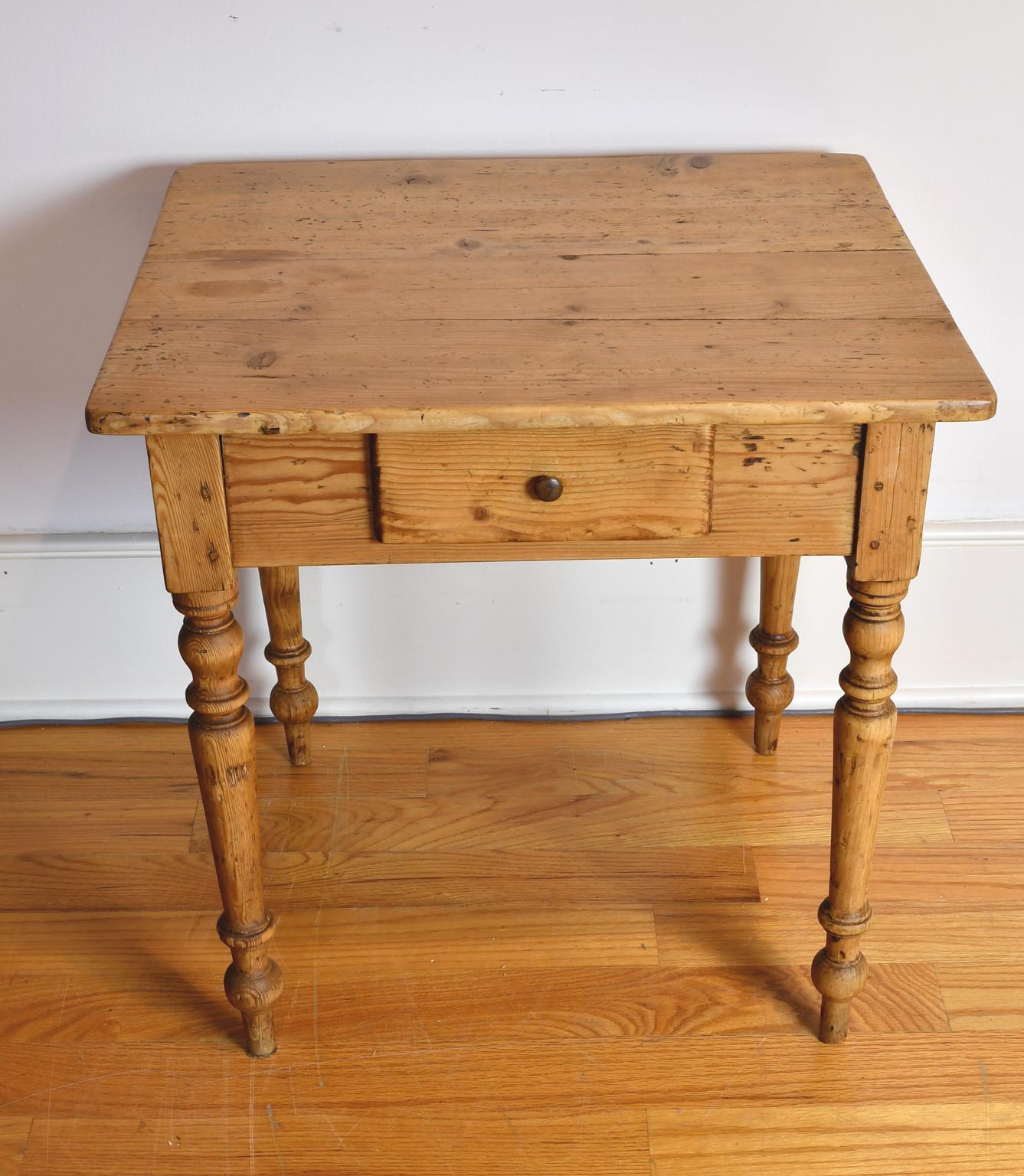 Une charmante et rare table de campagne européenne en pin couleur miel avec un plateau carré sur une base avec des pieds tournés et offrant un tiroir de stockage profond avec un bouton en bois tourné original. La menuiserie comprend des clous en