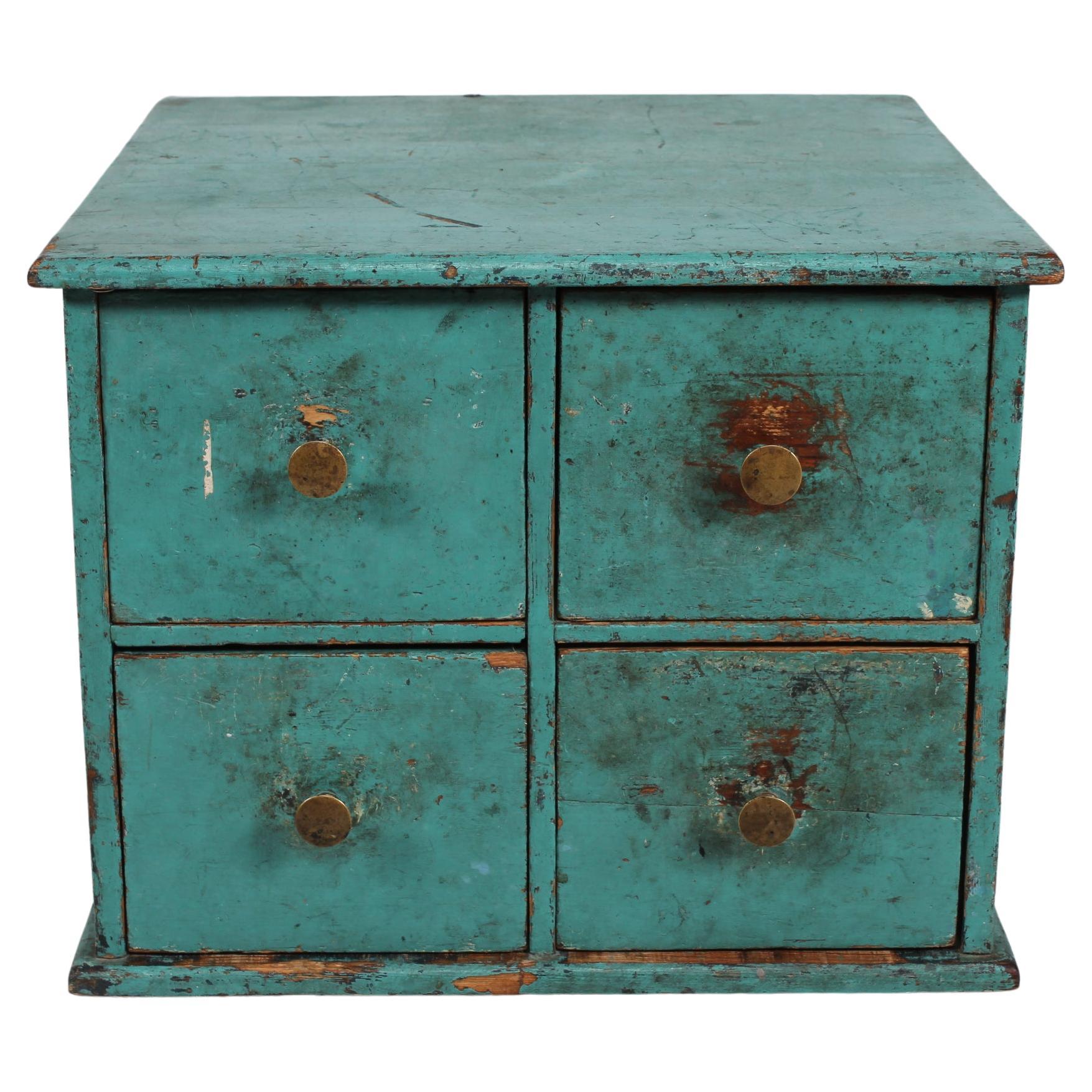 Small antique Swedish chest of drawers/ filing cabinet made of solid pine with turquoise/petroleum green paint patinated from wear and tear.
The small chest of drawers has four drawers with brass knobs. 
Made in the late 19th century