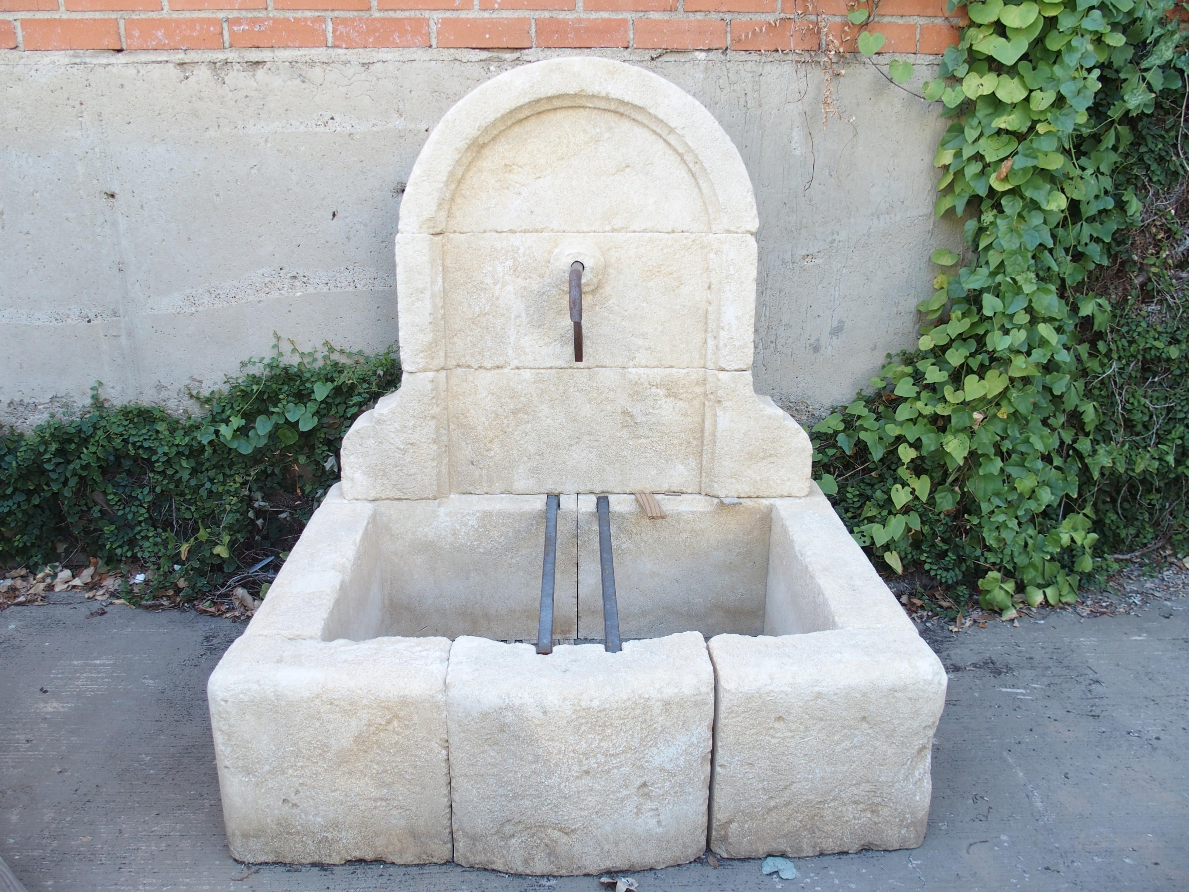 From Provence, France, this small limestone wall fountain has a high arched top with ogee carvings at the base of the wall. A thick molding with a chamfered edge adorns the interior of the wall, which is comprised of three stones. The middle stone