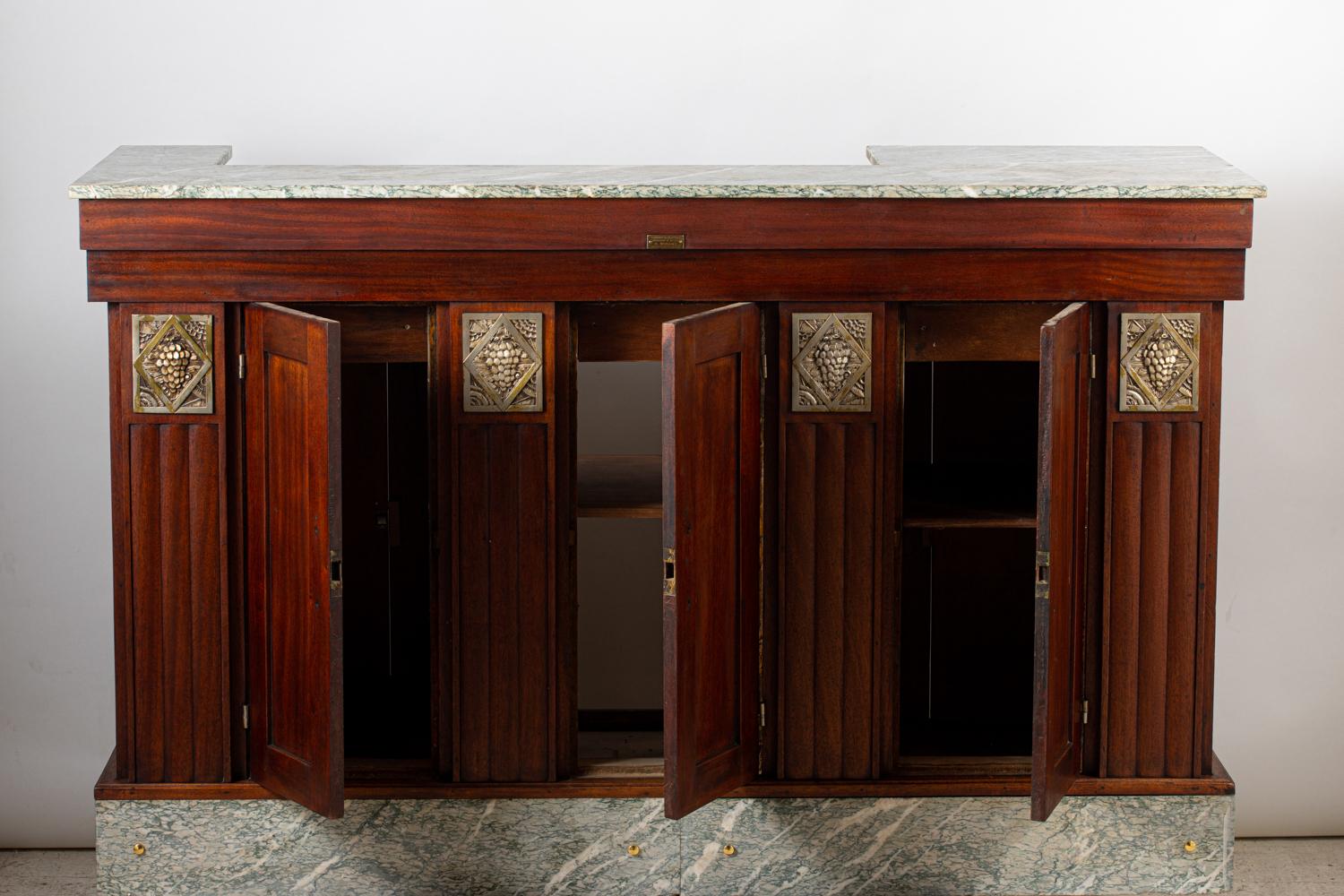 Nice bar from the Art Deco period of small size, opening with drawers and doors on both sides.
It's in sipo with ornaments with a bunch of grapes in silvered bronze.
The top and plinths are lined with Vert d'Estours marble.
The interior is lined