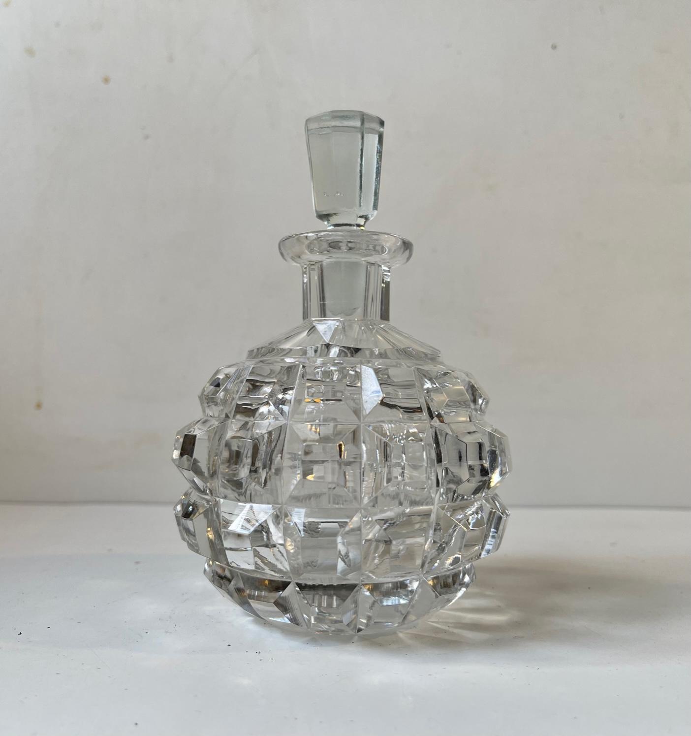 Small stylized round crystal decanter cut with cushion shaped patterns and set with a faceted stopper. Probably made by either Holmegaard or Lyngby in Denmark during the 1930s. Reminiscent in style to similar pieces from Baccarat and Daum. It has a