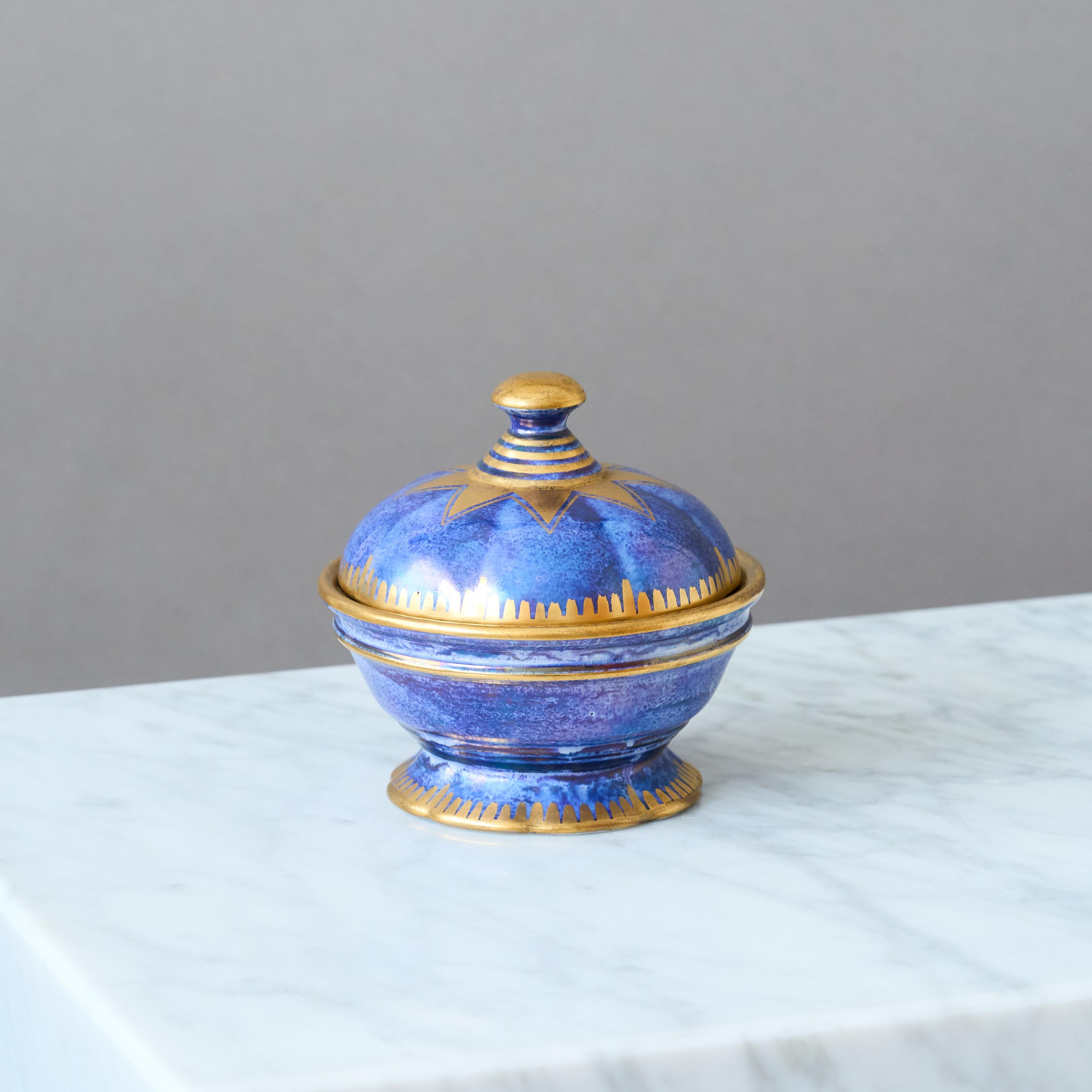 A small, blue, lidded bowl with amazing lustre glaze and hand painted gold details. Swedish Grace / Art Deco.
Made by Josef Ekberg at Gustavsberg, Sweden, 1930.

Great condition. 
Signed 'JE', '1930' and stamped with makers mark.

JOSEF EKBERG