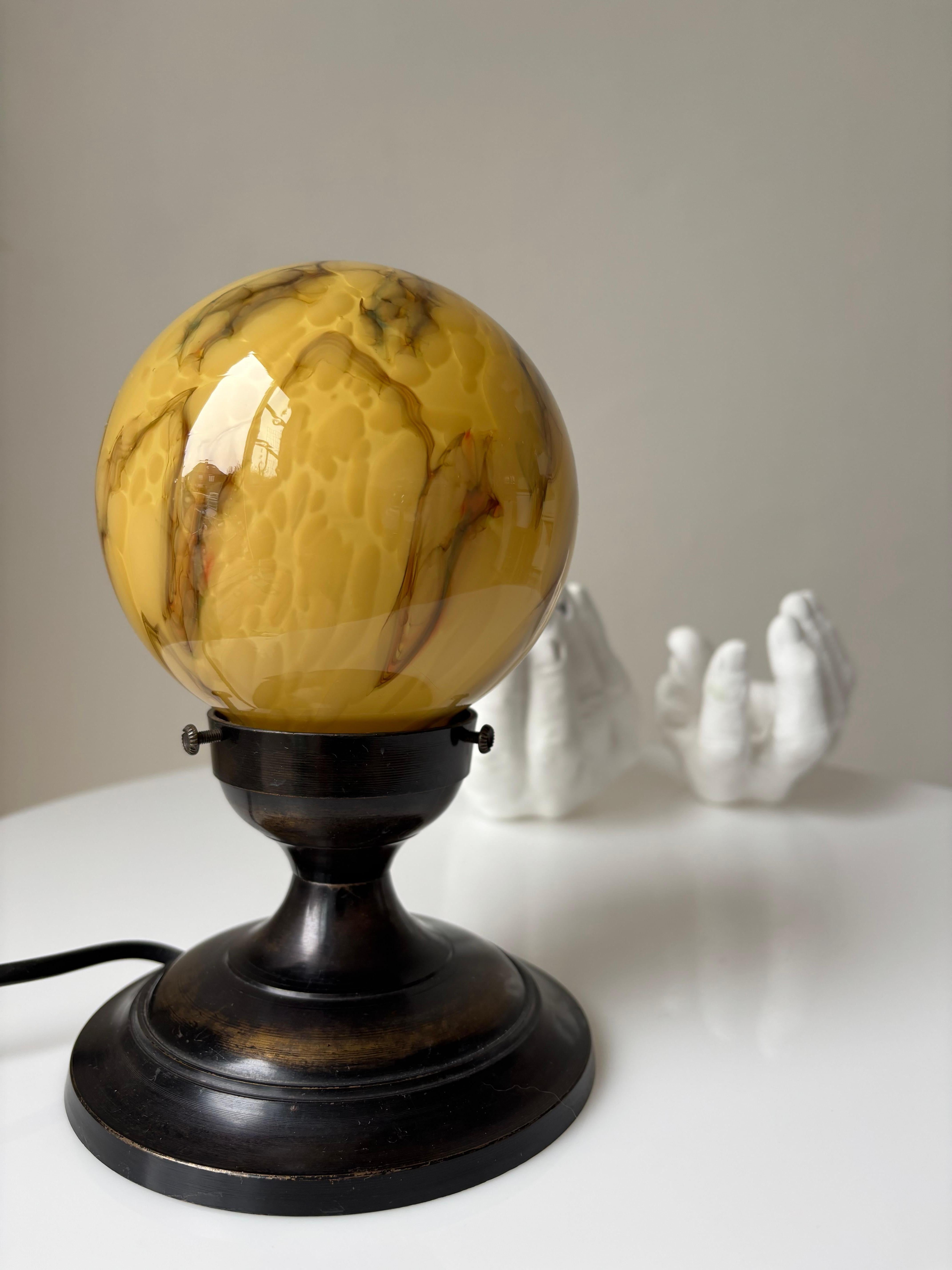 Small Art Deco lamp with mouth blown amber, honey and brown colored marbled glass globe top on bronze foot mount. Manufactured in the 1930s. 
Beautiful vintage condition. 
