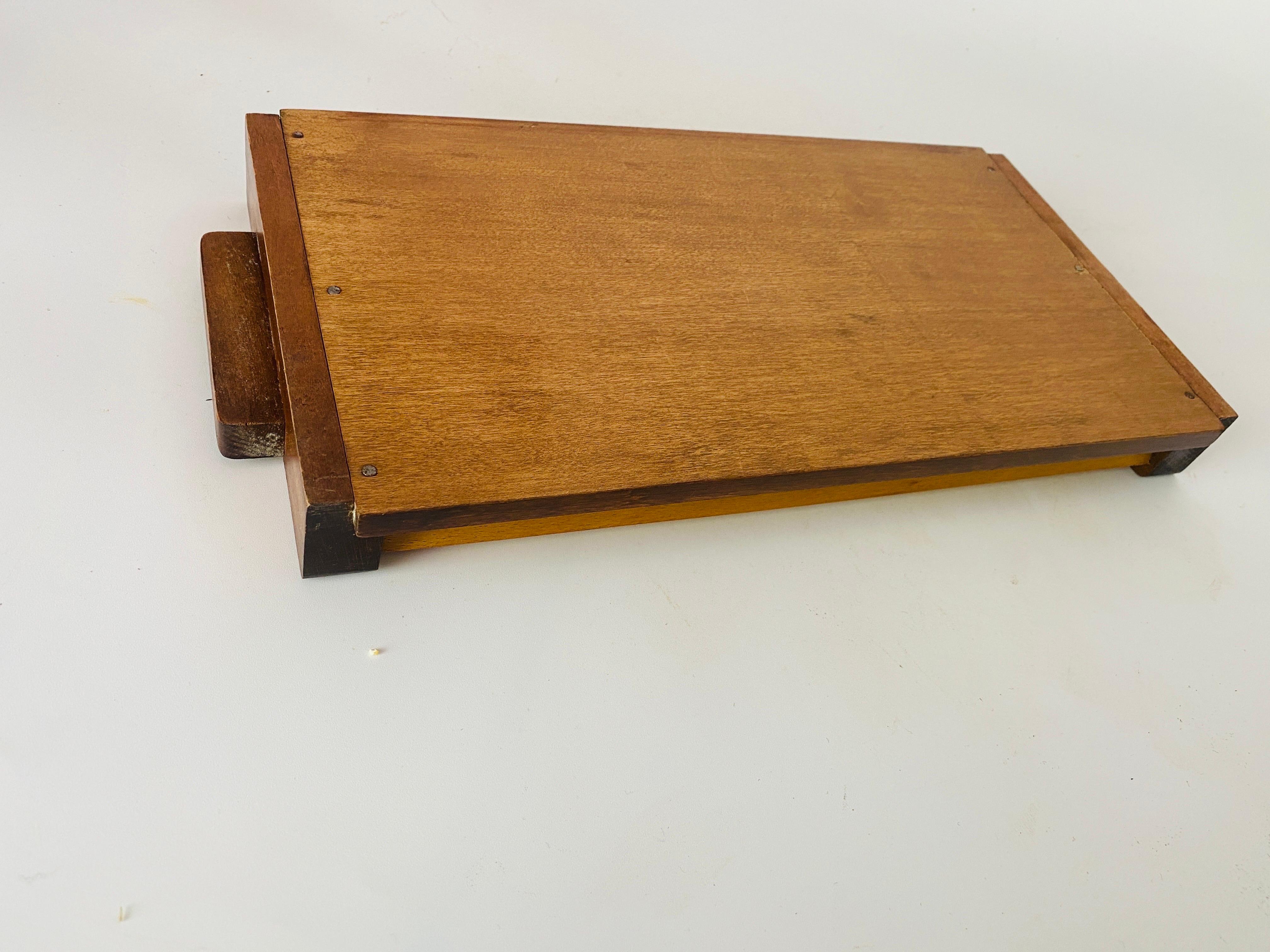 This tray is a tray from the Art-Deco period. It is in wood, , Its shape is rectangular, and ends with two wooden handles. Its color is Beige and Brown , it was made in the 1940s in France.