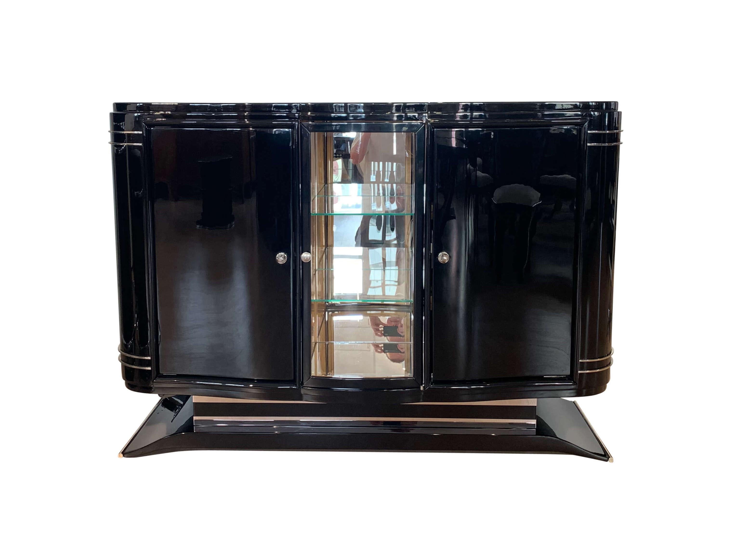 Small Art Deco sideboard / buffet, black lacquer, nickel, France circa 1925

Small black Art Deco sideboard with display cabinet / bar compartment from France circa 1925.
Original heavy metal trim and decorative handles, some of them newly nickel