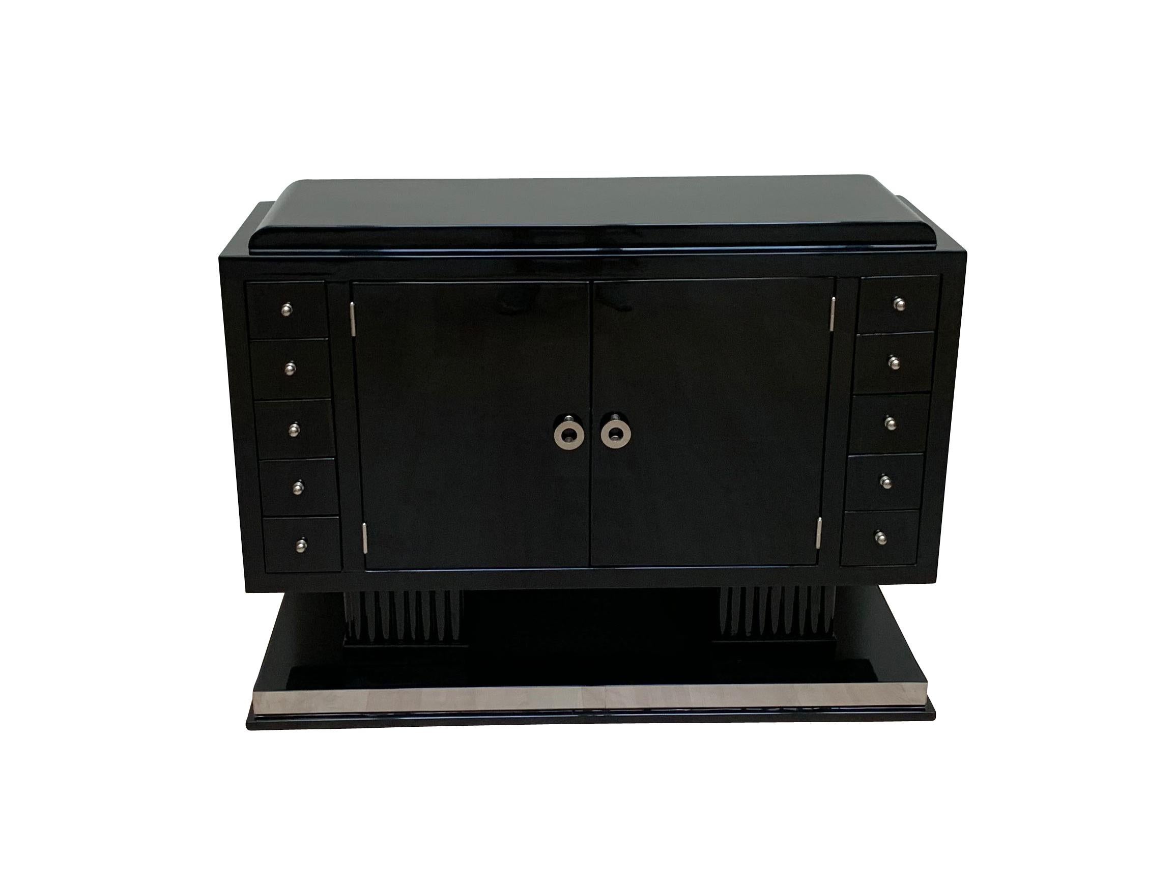 Wonderful small Art Deco sideboard from France, circa 1930.

Walnut lacquered with black piano lacquer (Polyurethane) and polished.
Very special composition with 10 little drawers and 2 doors at the front.
Two cannelures pillar legs, standing on