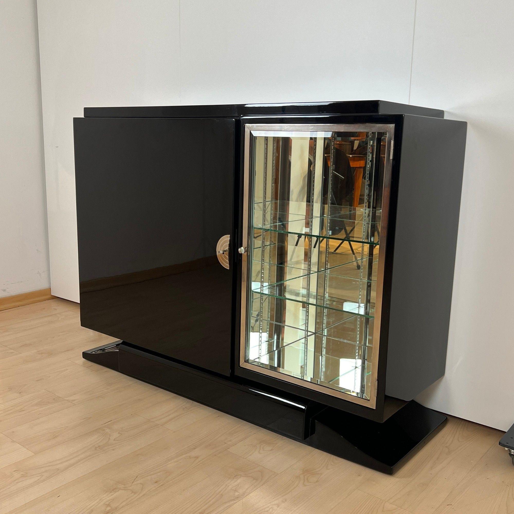 Small Art Deco Sideboard with glass cabinet compartment from France around 1930.
Black piano lacquer on wood, high gloss polished. Standing on a curved, typical Art Deco base and stepped wooden panel at the top.
On the right is a display cabinet