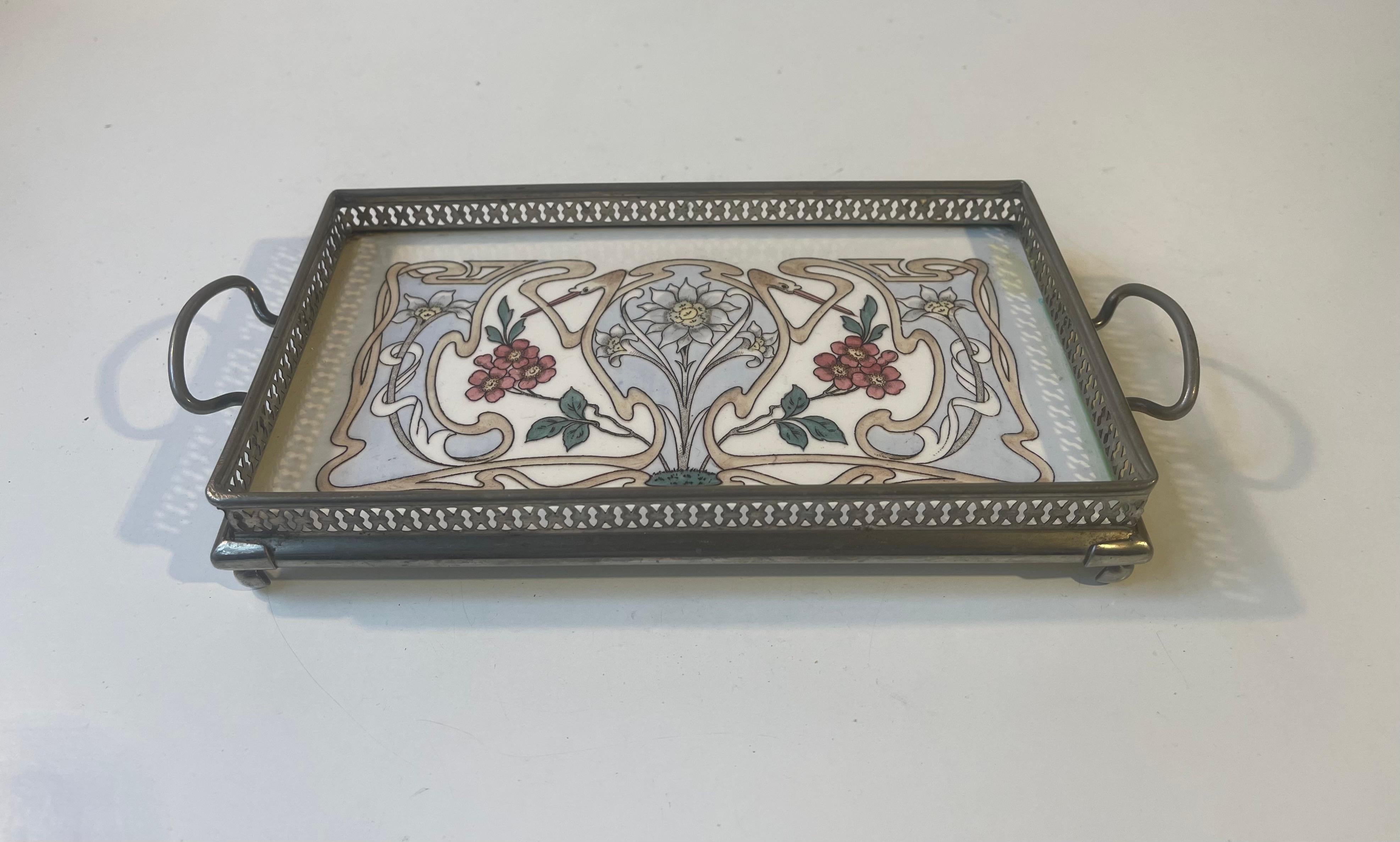 A decorative small sized rectangular tray in perforated nickel-plated metal and hand-painted porcelain. The stars of this motif are two stylized swans that wraps around floral decorations. Stamped decor 1711 and some other numerals to its backside.