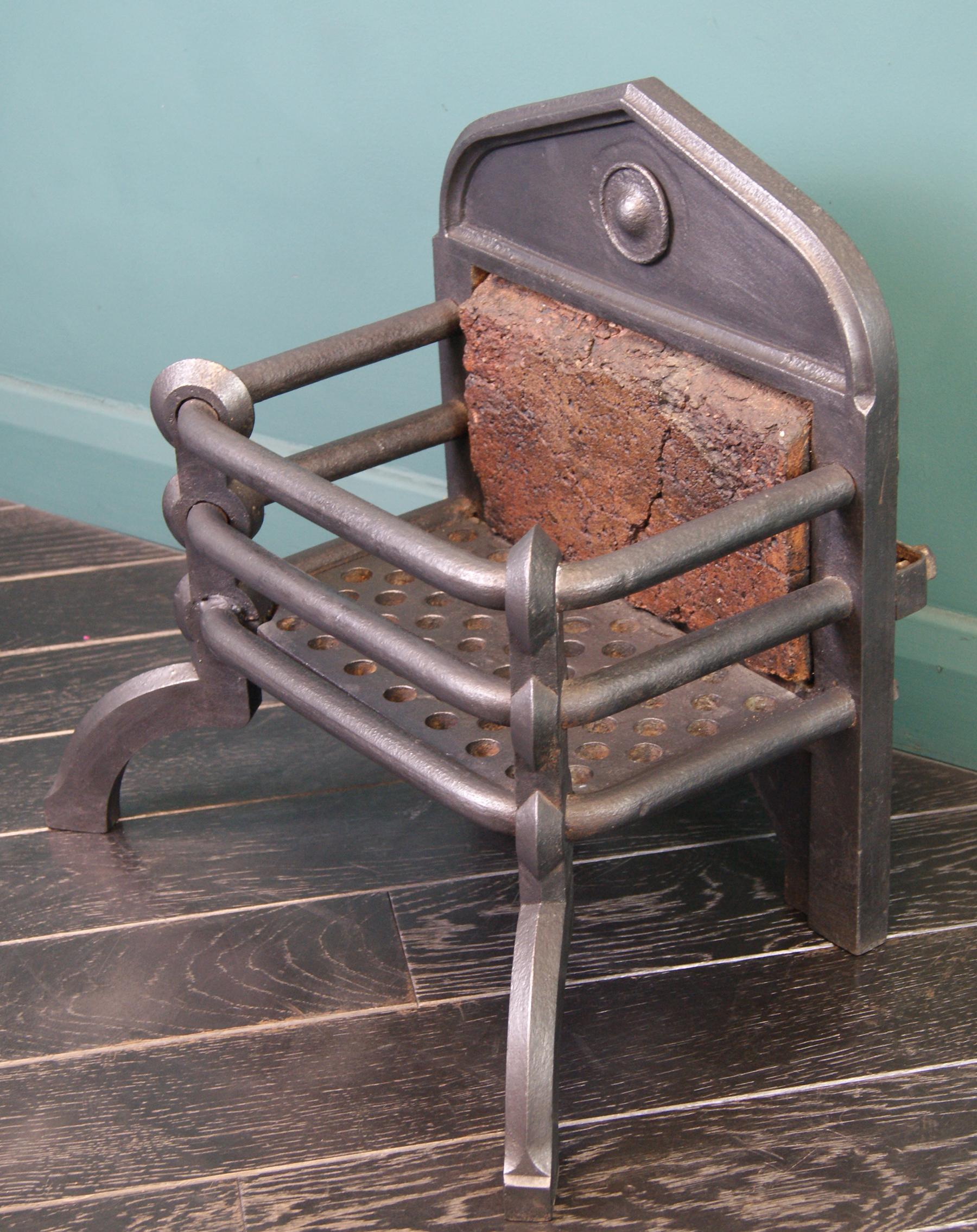 A small Arts and Crafts fire basket in black wrought iron with central roundel detail to arched fire back. Fire brick present to radiate heat. Restored.
Width at rear: 14