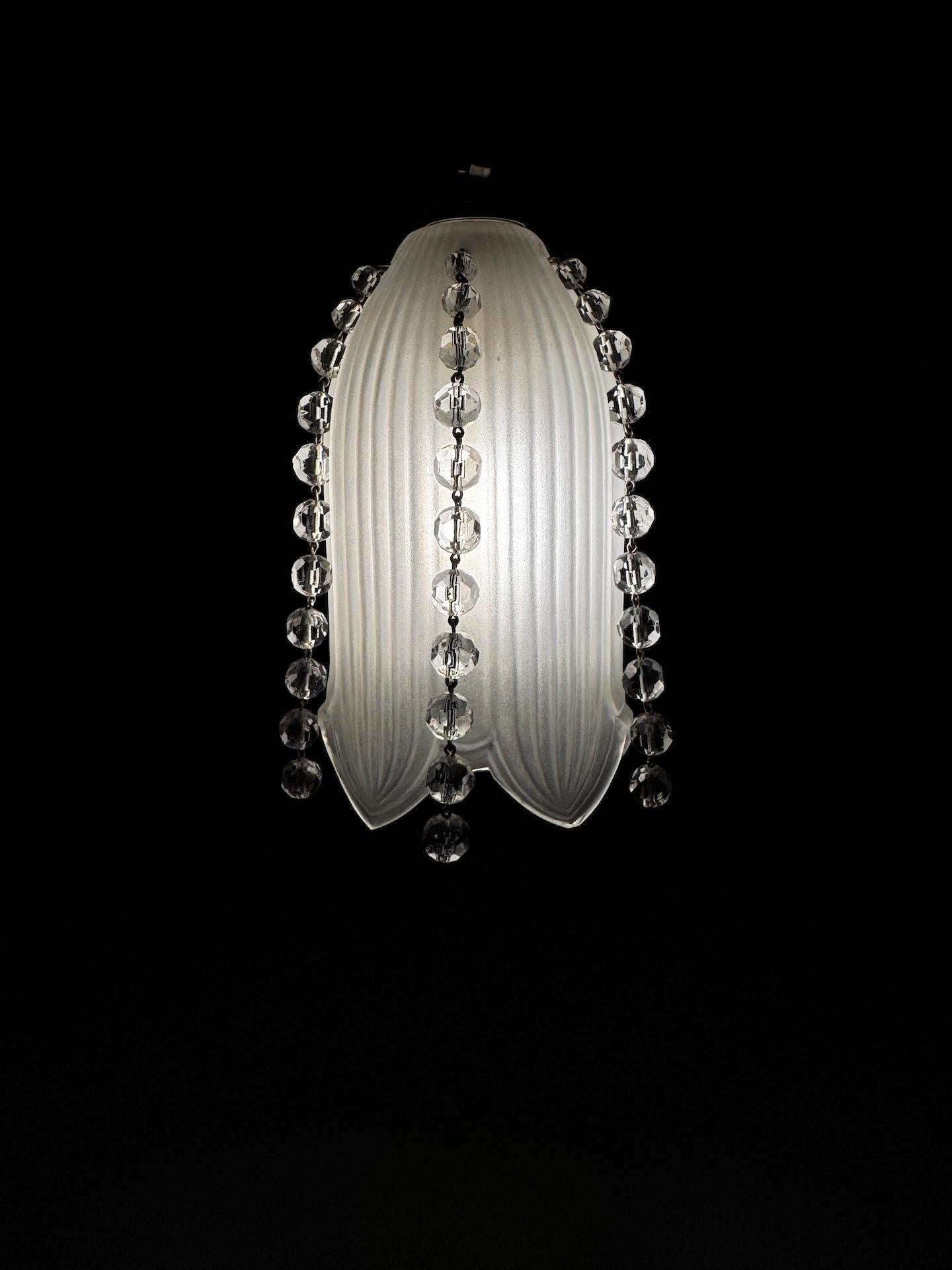 Piccoli pendenti in cristallo Baccarat, periodo Art Deco, regolabili in altezza a seconda delle tue esigenze.
Un ciondolo degli anni '30 molto delicato. Si tratta di un tulipano a forma di bucaneve circondato da cinque pendenti di cristallo.
Il