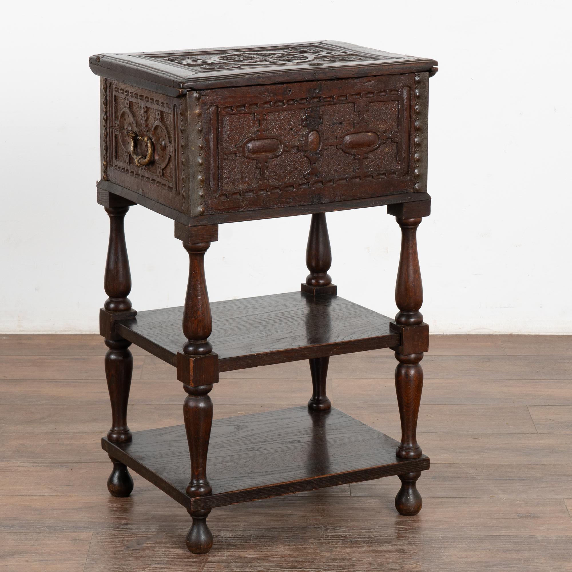 Heavily carved small baroque oak chest resting on later dated oak stand with two shelves. Note in the central circular carving along the top, the visible date of 1688 and initials AN. Chest is reinforced with iron corners; note original long
