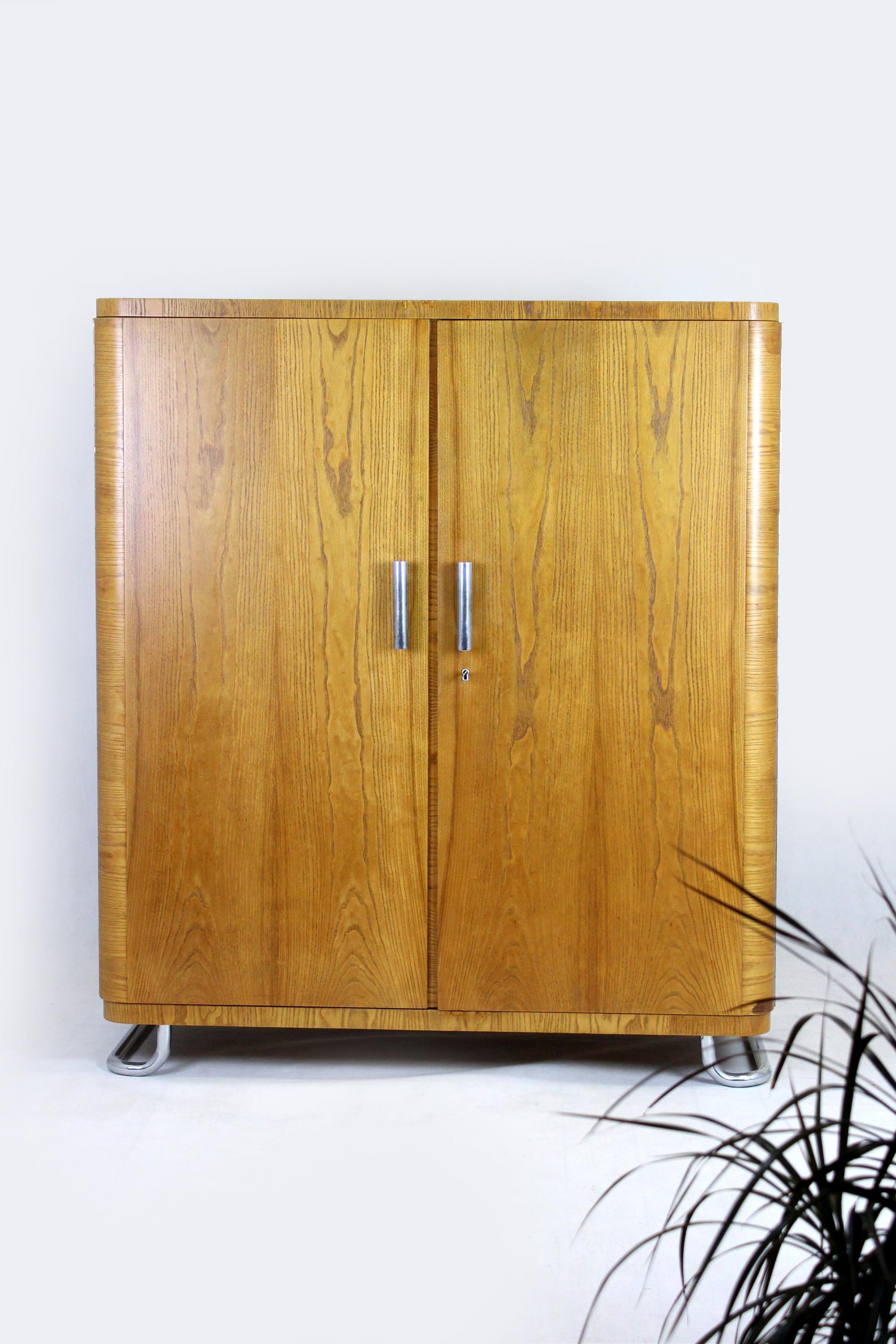 This Bauhaus-style wardrobe was produced by Hynek Gottwald in Czechoslovakia in the 1930s. 
Features two doors and three shelves. The wardrobe stands on chromed feet and has chromed cylinder handles. 
Very good condition, clean.