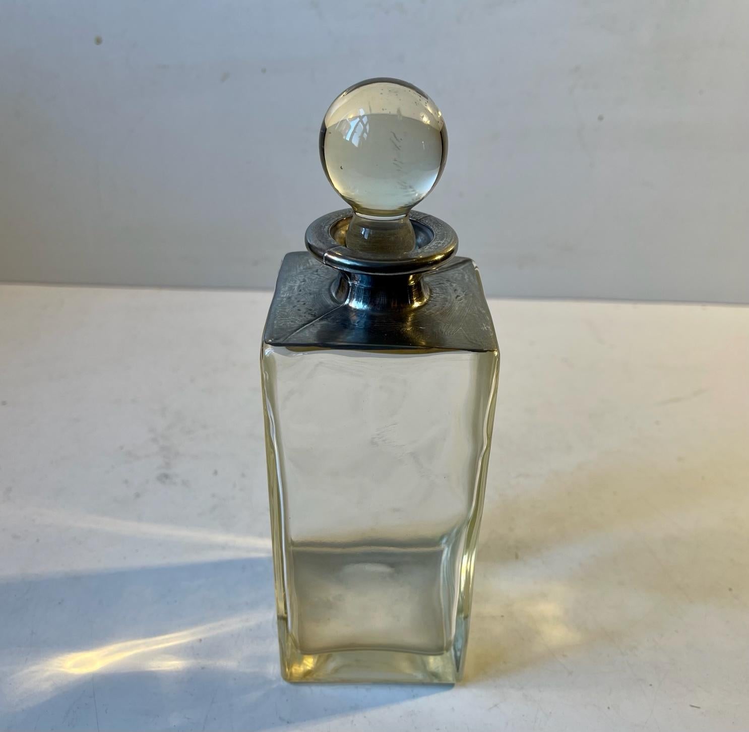 Small rectangular decanter in thick glass decorated with a top in pewter/white metal. Distinct Bauhaus styling. Manufactured in Germany or Scandinavia circa 1930. Measurements: H: 20/16 cm, W/D: 7 cm. Capacity: 0.4 liter.