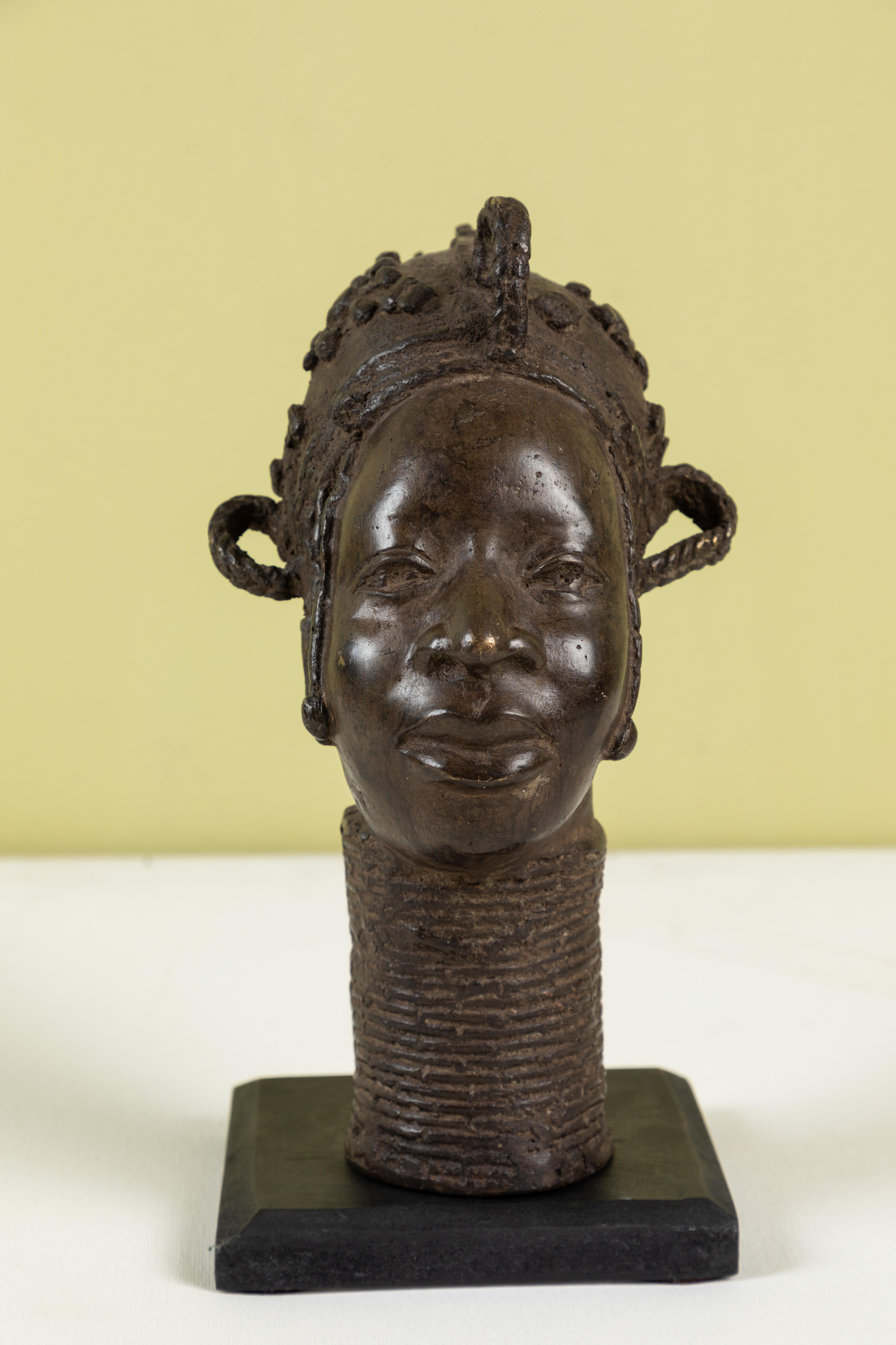 Benin bronze head on painted wood stand.