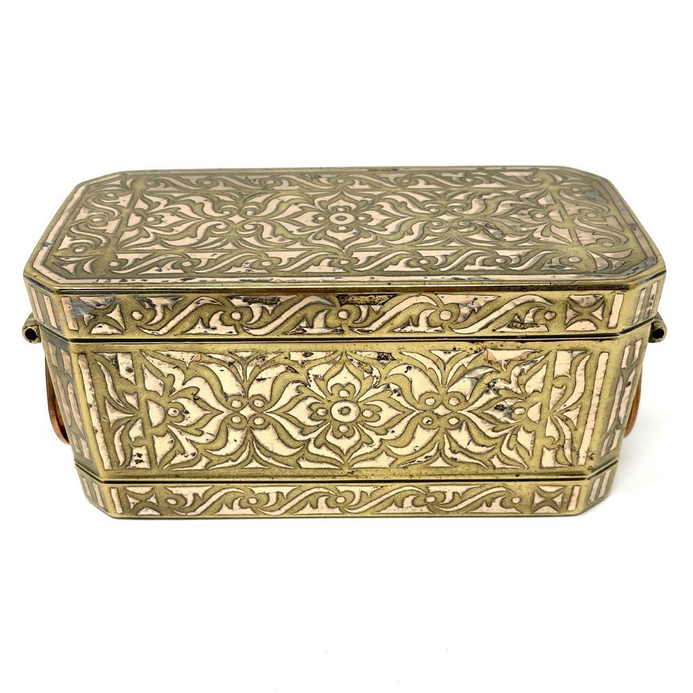 Small Betel Nut Box, Maranao, Southern Philippines (Mindanao).
A mixed metal box having a bronze/brass body with bordered silver/copper inlay design overall of a symmetrical floral tendril vine pattern referred to as “the okir pattern”,  a