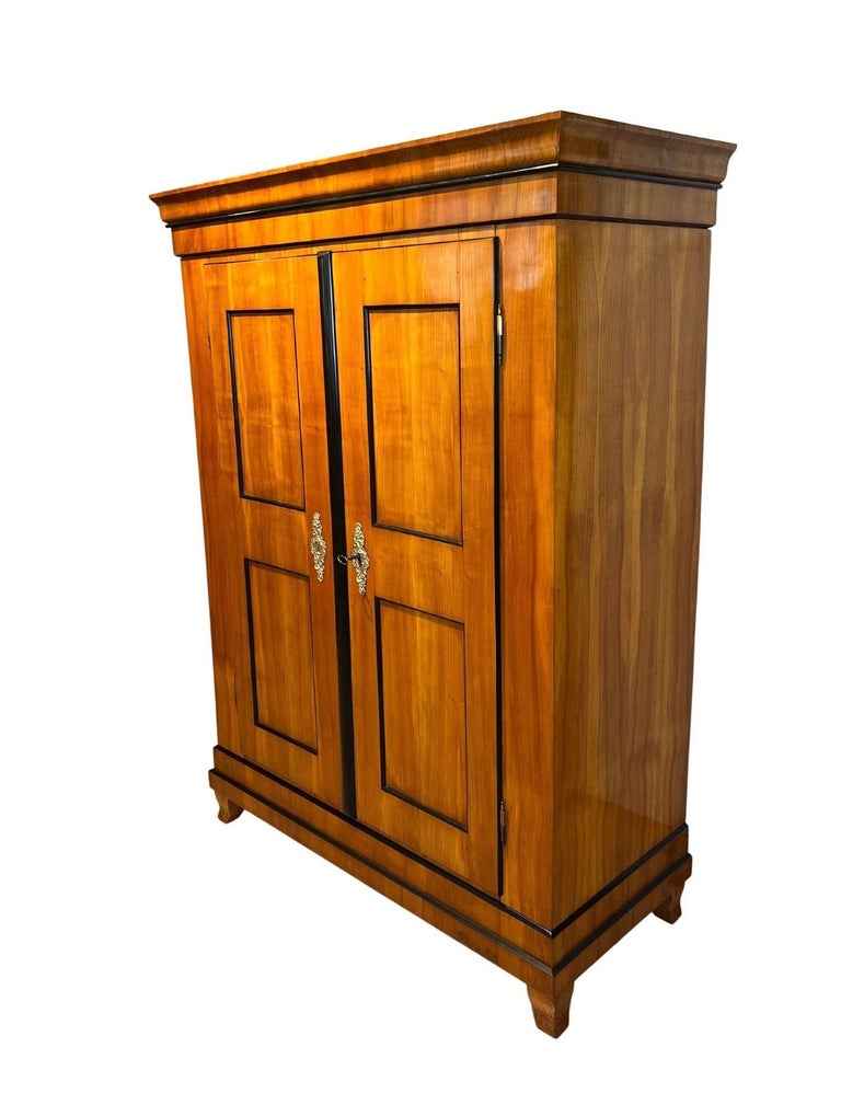 Small Biedermeier Armoire, Cherry Veneer, South Germany circa 1825
 
Cherry veneer on spruce and solid cherry wood. Two doored with filling fields. Original pressed brass fittings. Original box lock. Interior covered with 4 shelf boards in black