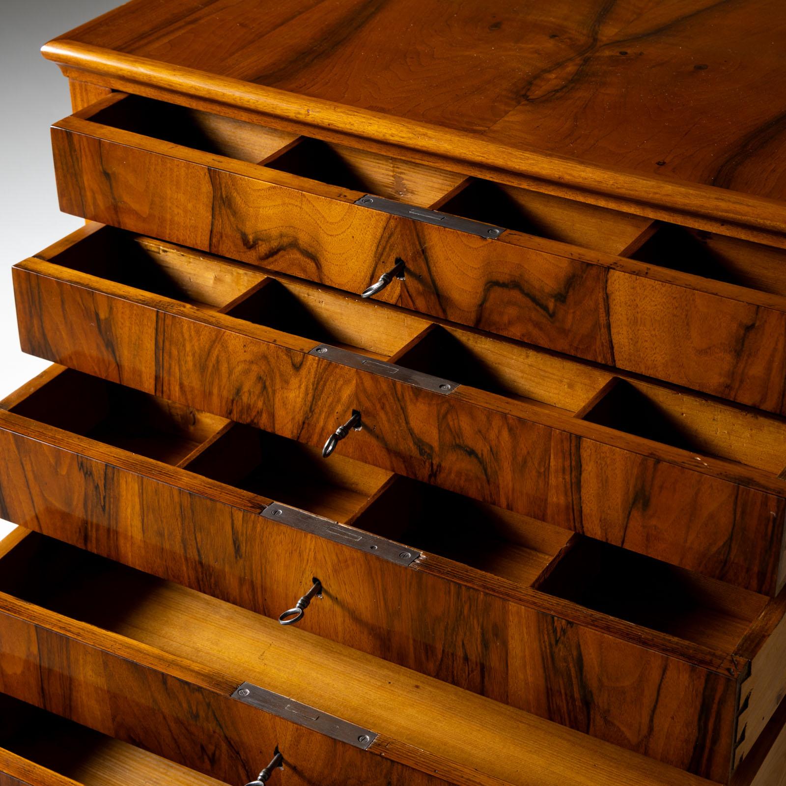 Small walnut veneered Biedermeier chest of drawers with five drawers. The chest of drawers rests on square tapered feet and has been professionally restored and polished by hand. The top three drawers are fitted with a lattice-shaped divider on the