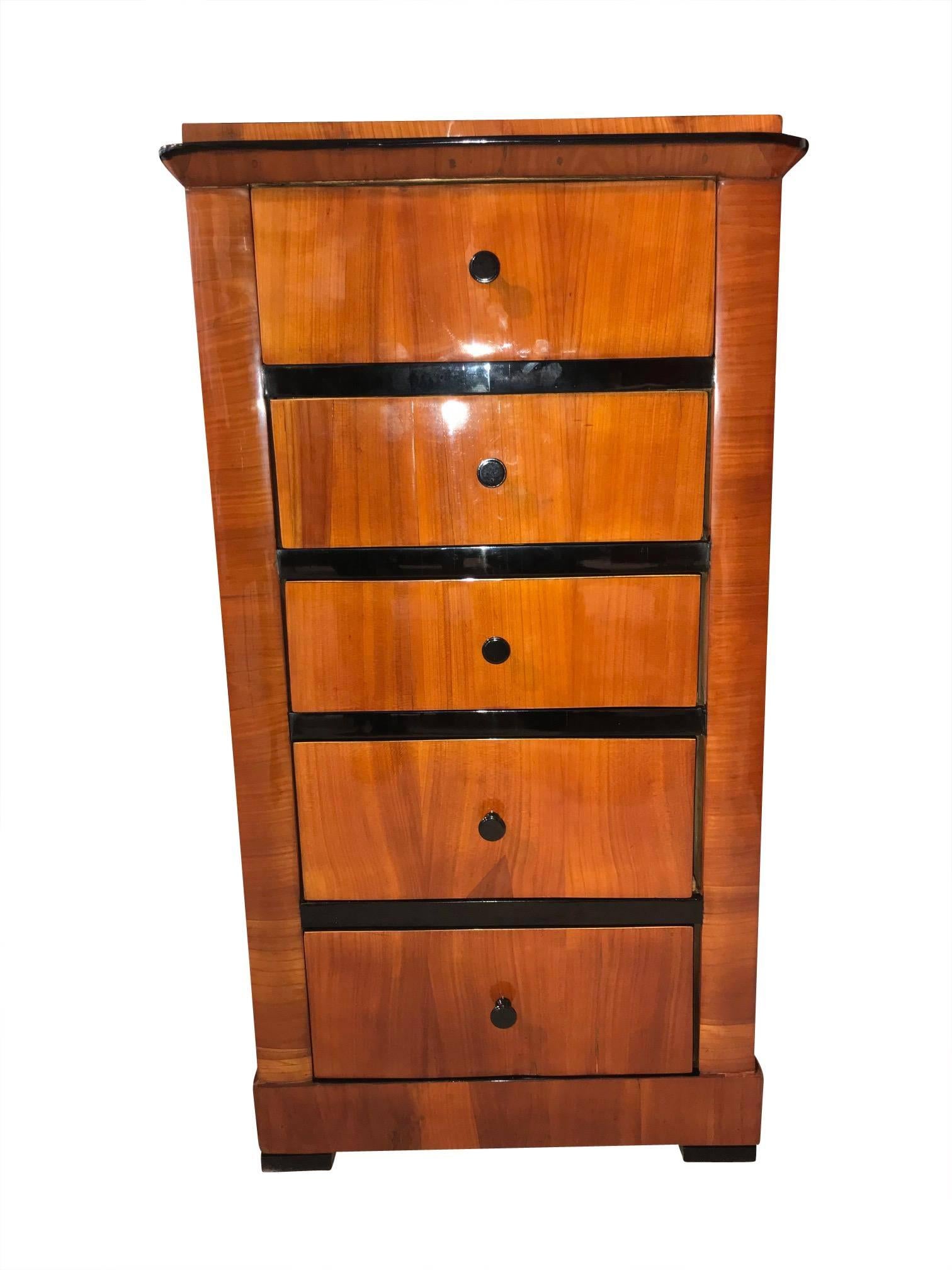 Rare, petite Biedermeier pillar cabinet /chest of drawers. It has a beautiful continuous cheerywood veneer over the five drawers at the front, which are interrupted by thick ebonized crosspieces. It is shellac hand-polished and in great condition.