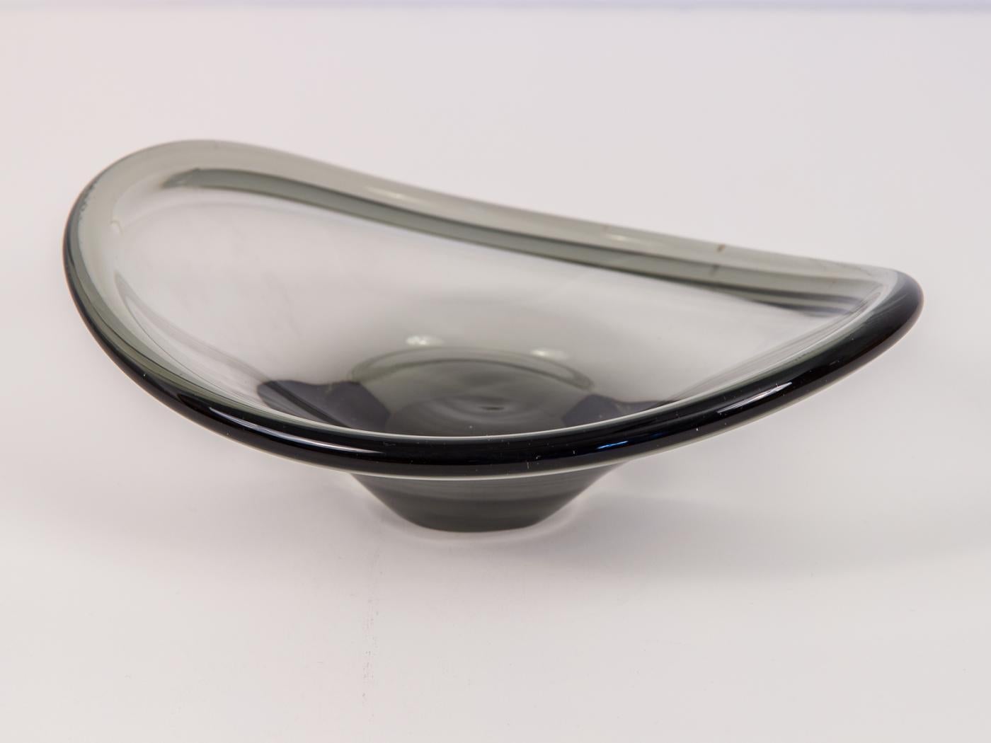 Small biomorphic smoked glass serving bowl. Designed by Per Lütken for Holmegaard in the 1940s, this petite, hand blown glass curvilinear bowl has a elegantly sculpted look. Etched on the underside with the Holmegaard company name and edition number.