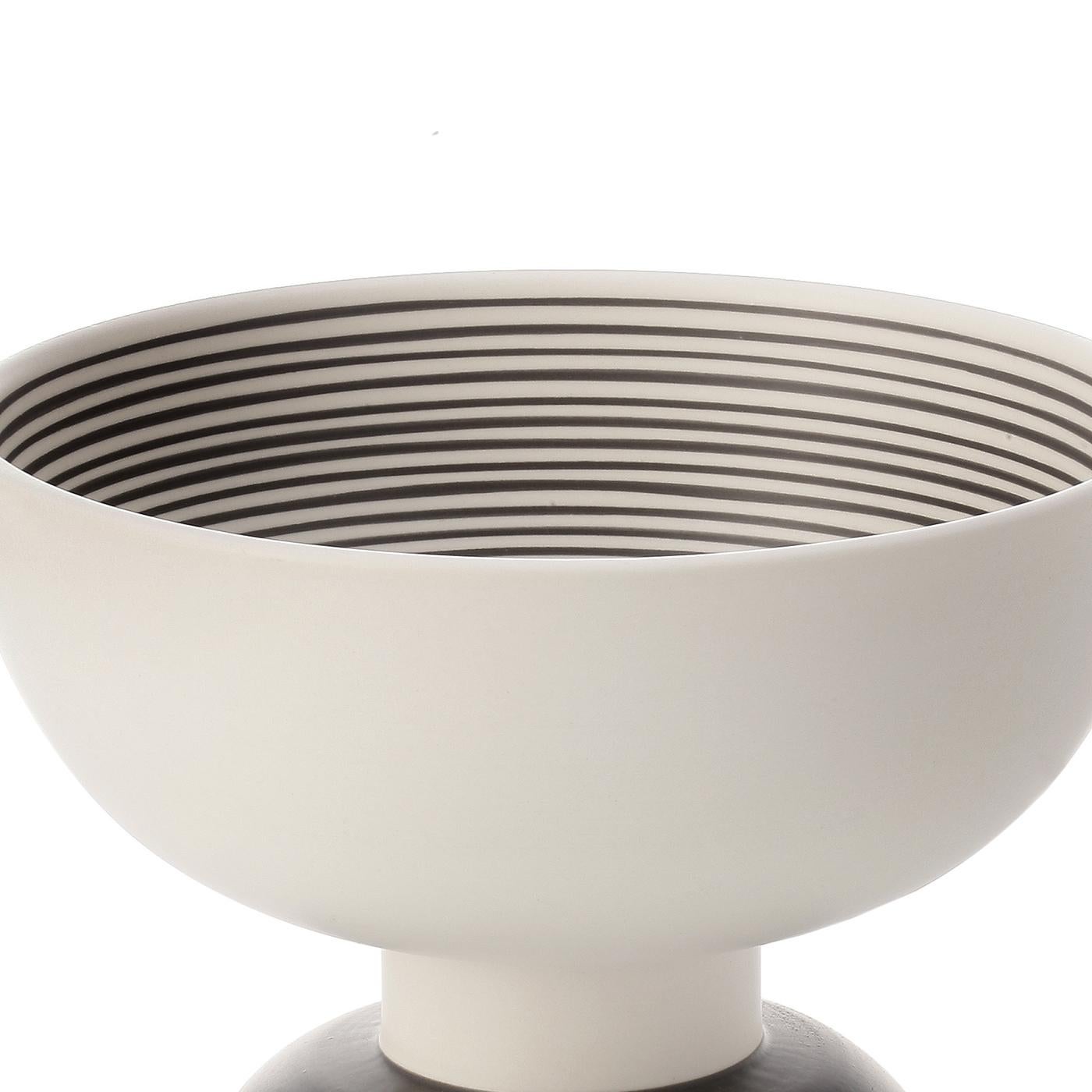 This striking centerpiece in white clay has an external finish in black on the base and white on the body, with an internal decoration of fine, parallel black lines over the white finish. This minimalist and geometric piece was the result of