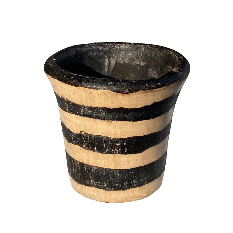 A small abstract black and white planter or candle holder. Created by a craftsman in Honduras, this lovely piece is solid and is created from either wood or ceramics. (It really does have a strange weight to it.) It is painted in concentric black