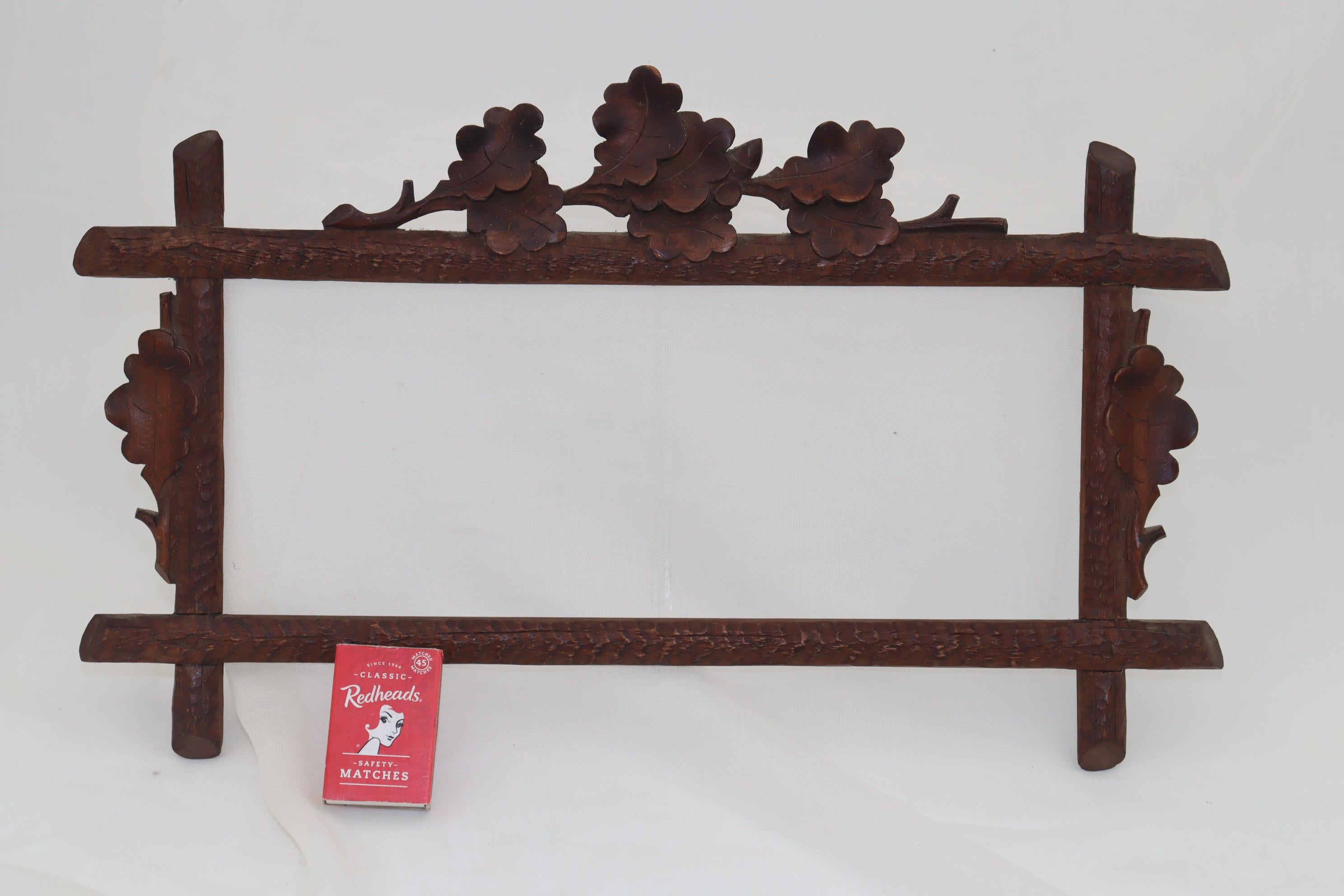 This small rectangular Black Forest picture frame has the sides carved to represent rough textured bark and is adorned with applied oak leaves on three sides. This would allow it to either hang on a wall or be supported on a stand. The width is 405