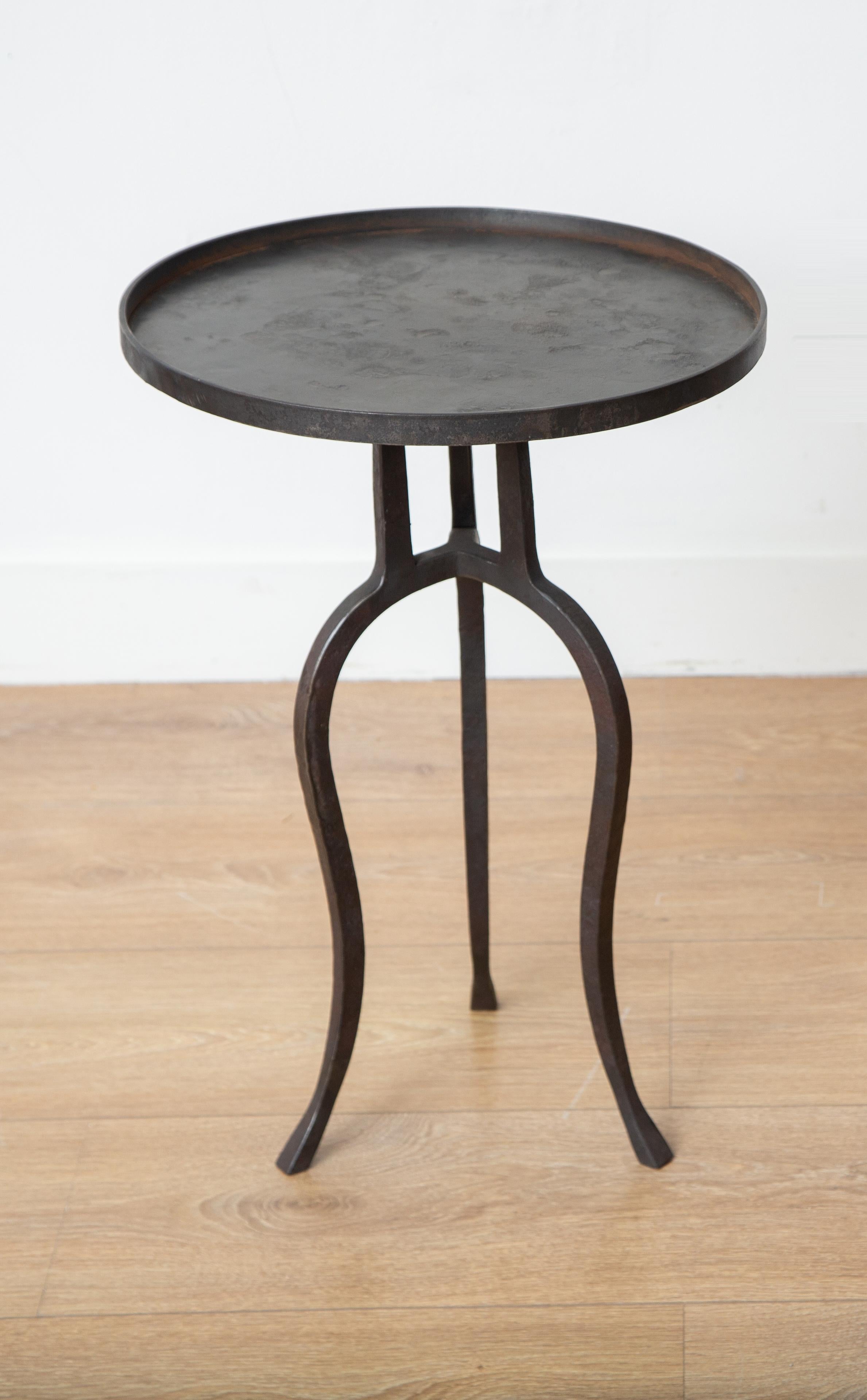 Small black iron side or drinks table, in stock.
This stunning wrought iron tripod side table is an eye-catching addition to any home decor. Its round top features a lip, and its hammered metal frame has a beautiful black patina that gives it a