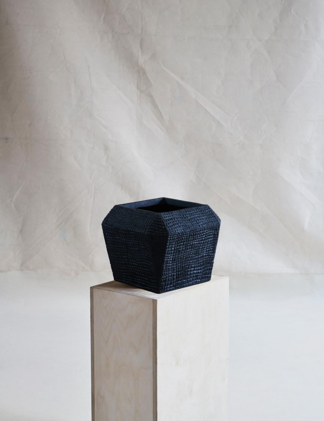 A small, stout geometric square vessel featuring a wide mouth, imprinted with a small repeating tactile texture.

For indoor or outdoor use, in covered environments.

Dimensions (in): 8