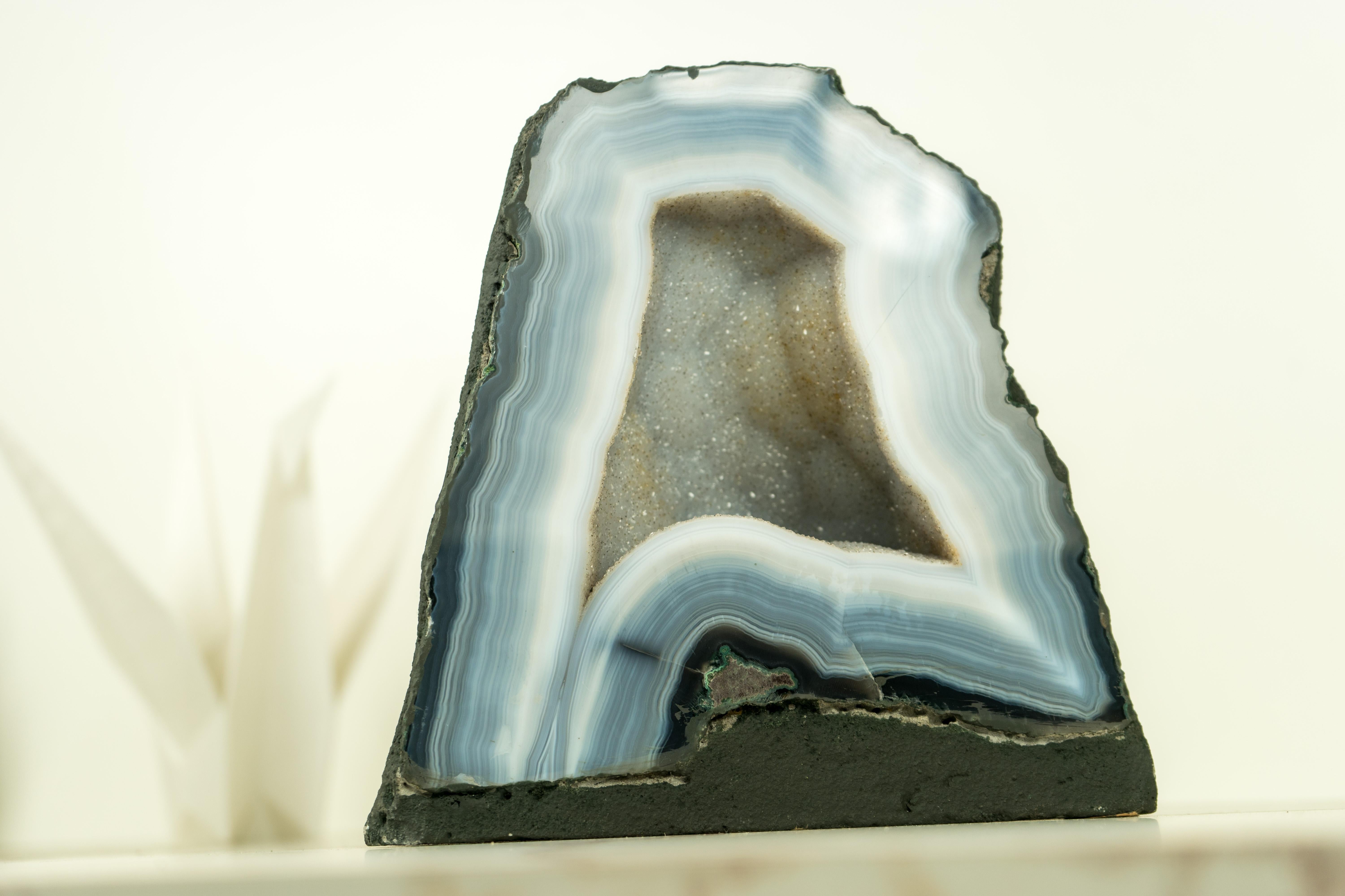 Small yet stunning, this Blue and White Lace Agate Geode brings numerous flawless natural agate laces, along with sparkly white galaxy crystals that form the beautiful aesthetics of the geode. It's undoubtedly a standout specimen for your space and