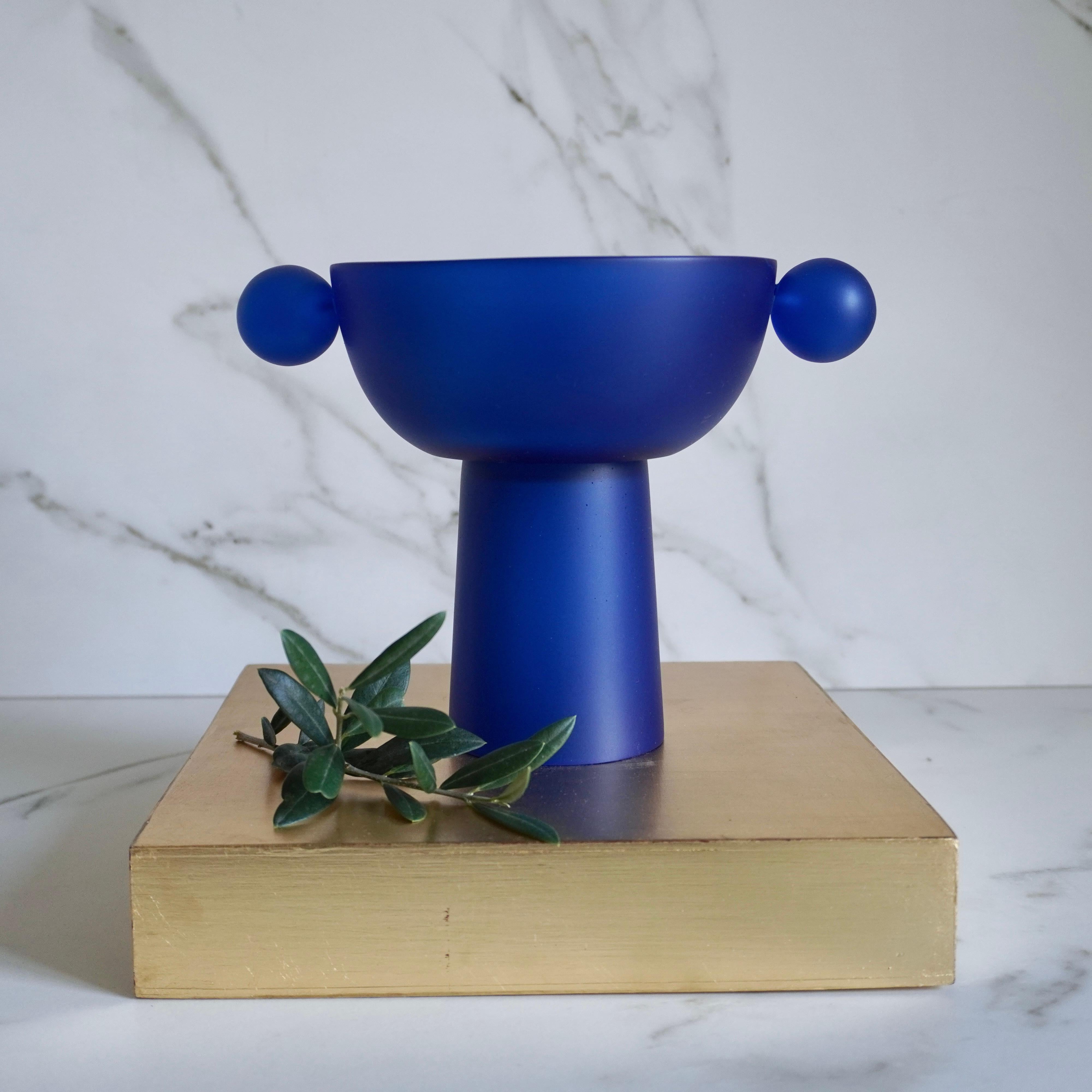 This small pedestal stands tall as a stately centerpiece or bookshelf display. The spheres give the piece a playful and modern look, making it a perfect statement piece for any space.

Color: Traslucid blue resin in satin finish.

Designed by