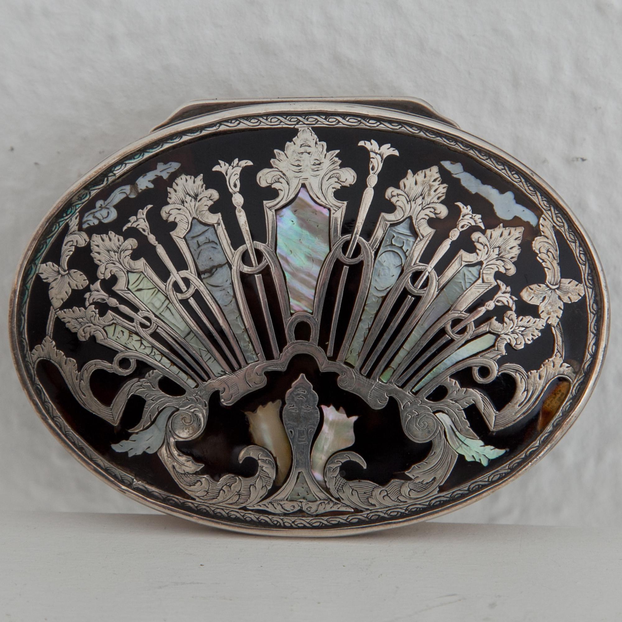 Oval lidded box with fan-shaped ornament on the tortoiseshell lid as well as mother of pearl and silver inlays.