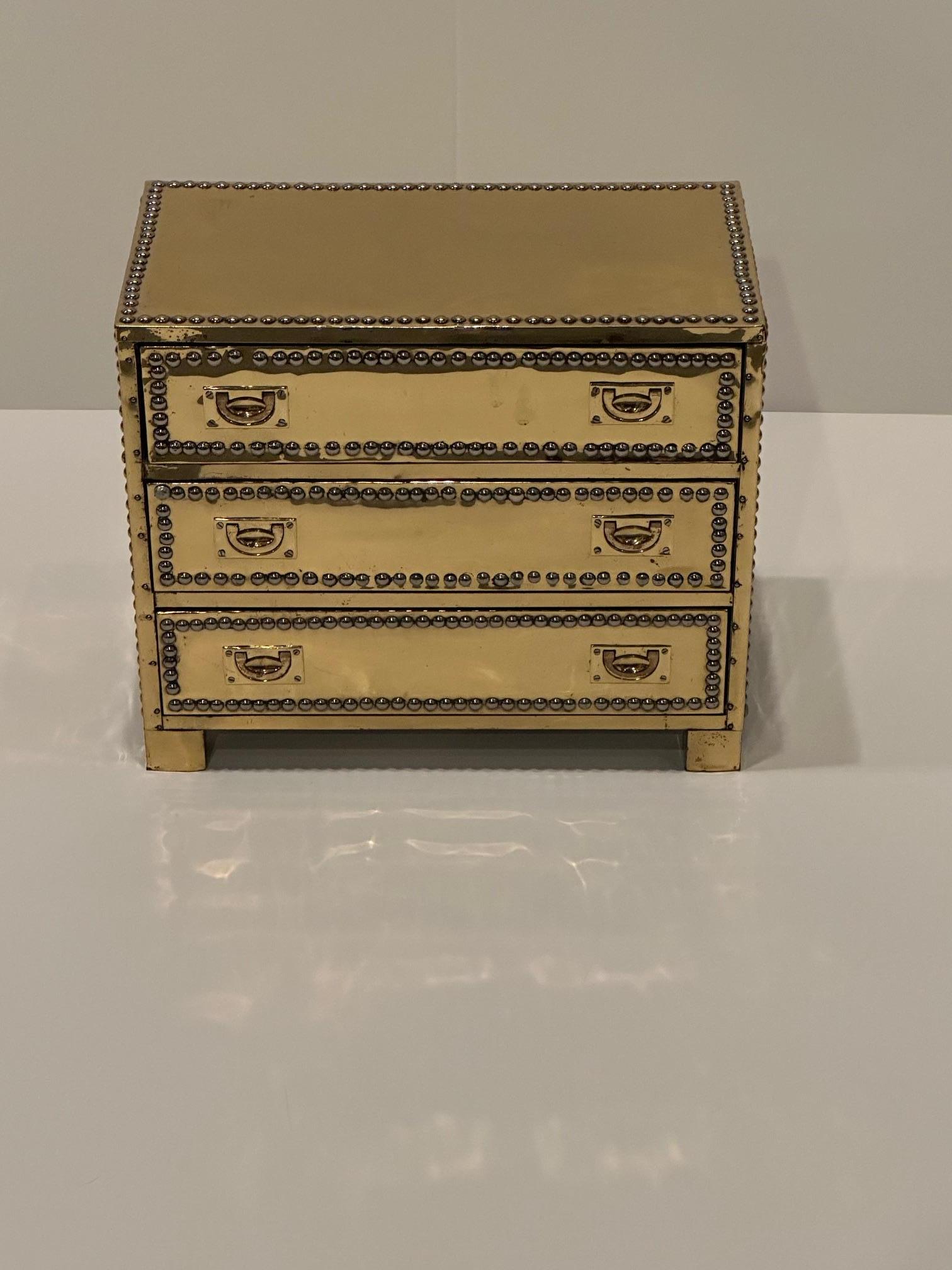 Small captivating brass over wood small chest having 3 drawers and nailhead decoration with recessed handles.