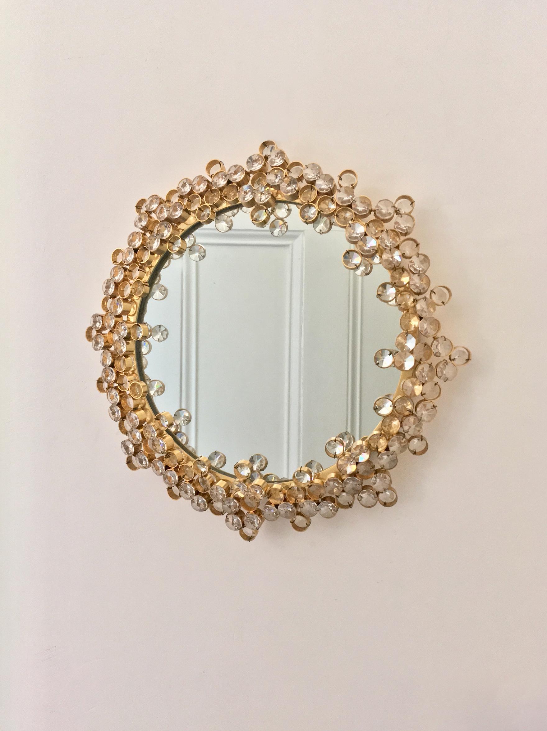 Un affascinante specchio circolare da parete con cornice in ottone dorato e cornice decorativa in cristallo di alta qualità. Attribuito a Palme & Walter (o Palwa), seconda metà del XX secolo.

Un pezzo ben progettato e costruito, con un piacevole