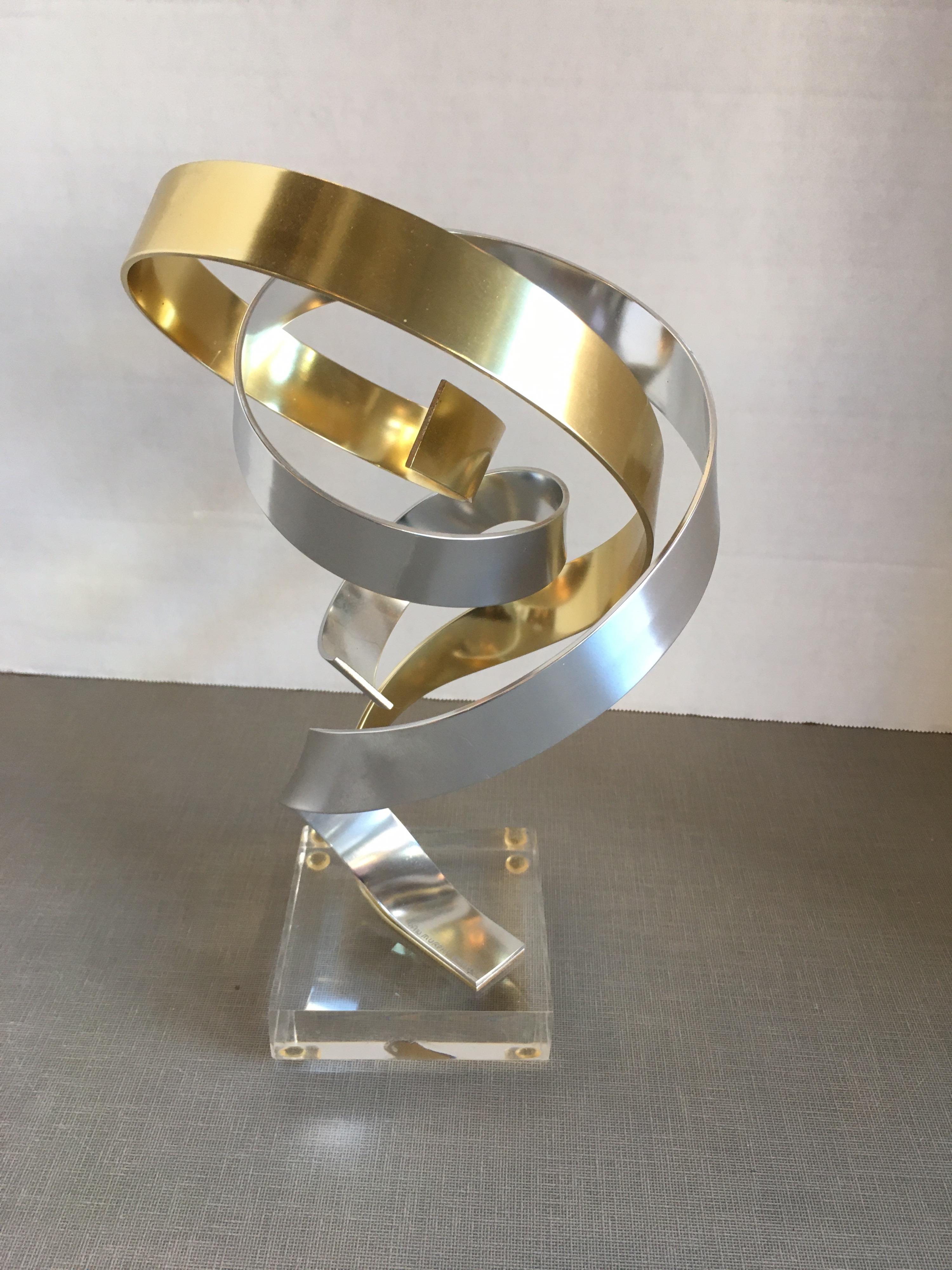Small brass and silver aluminum ribbon sculpture on a Lucite base by Dan Murphy.
