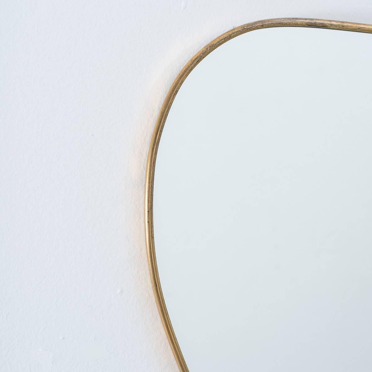 This quirky little mirror harks back to the well-known examples produced by Gio Ponti. Our mirror of a similar age to the Gio Ponti ones however, has a more free-form shape to it. It has a smooth brass surround frame, solid wooden backing and metal