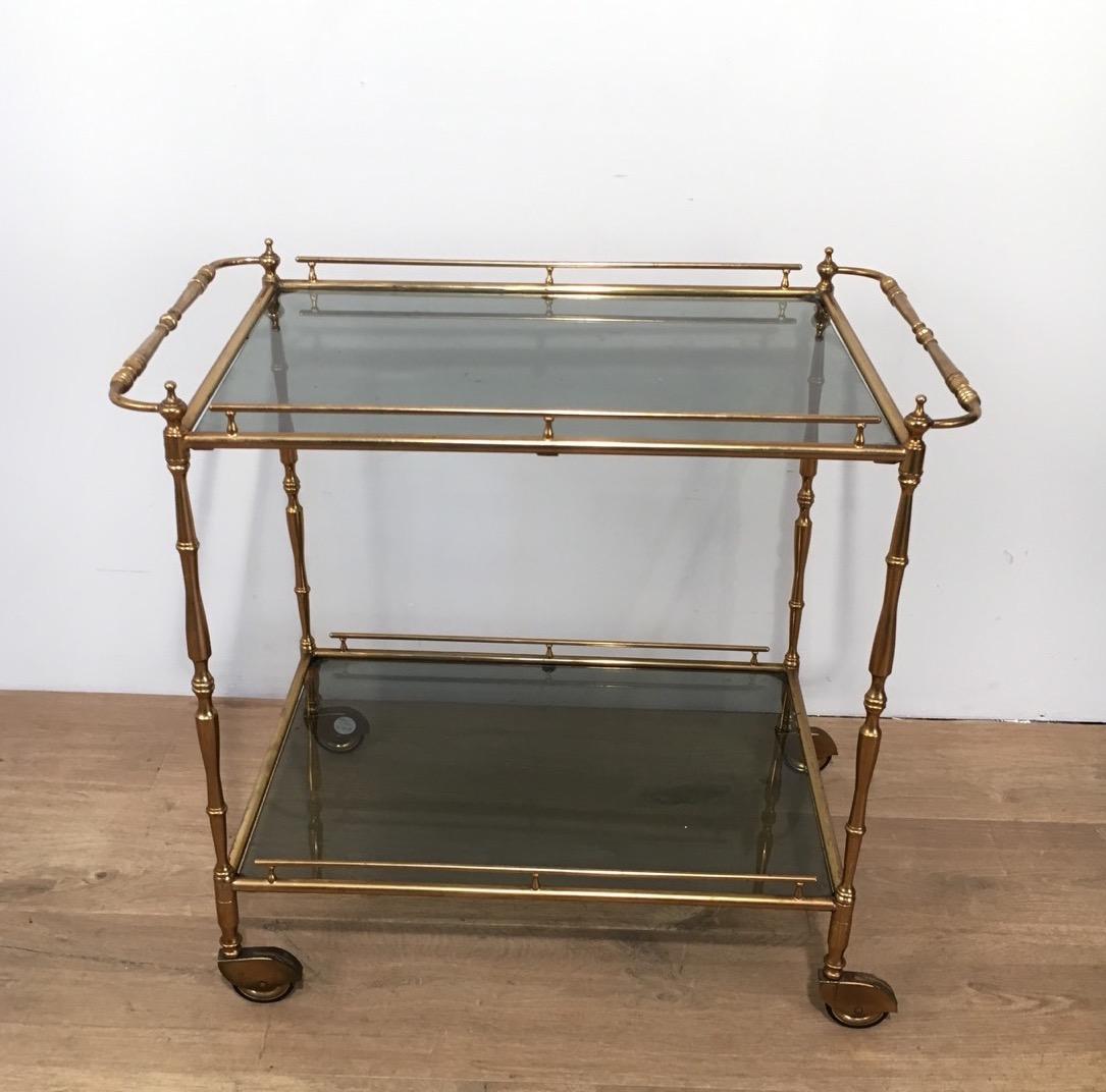 This small neoclassical trolley is made of brass with tainted glass shelves. This is a French work, circa 1940.