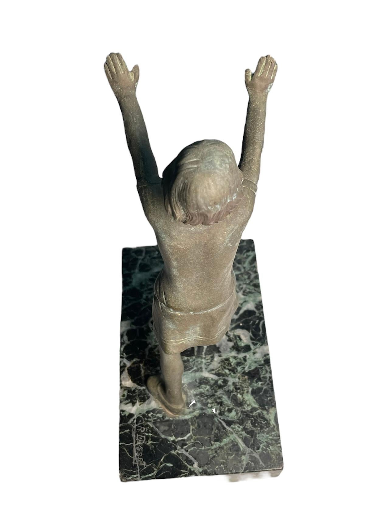 This is a small patinated bronze sculpture of a girl stretching herself and/or trying to push something. The sculpture is supported by a rectangular shaped black and white marble base. A corner of the marble is signed R.Desset.