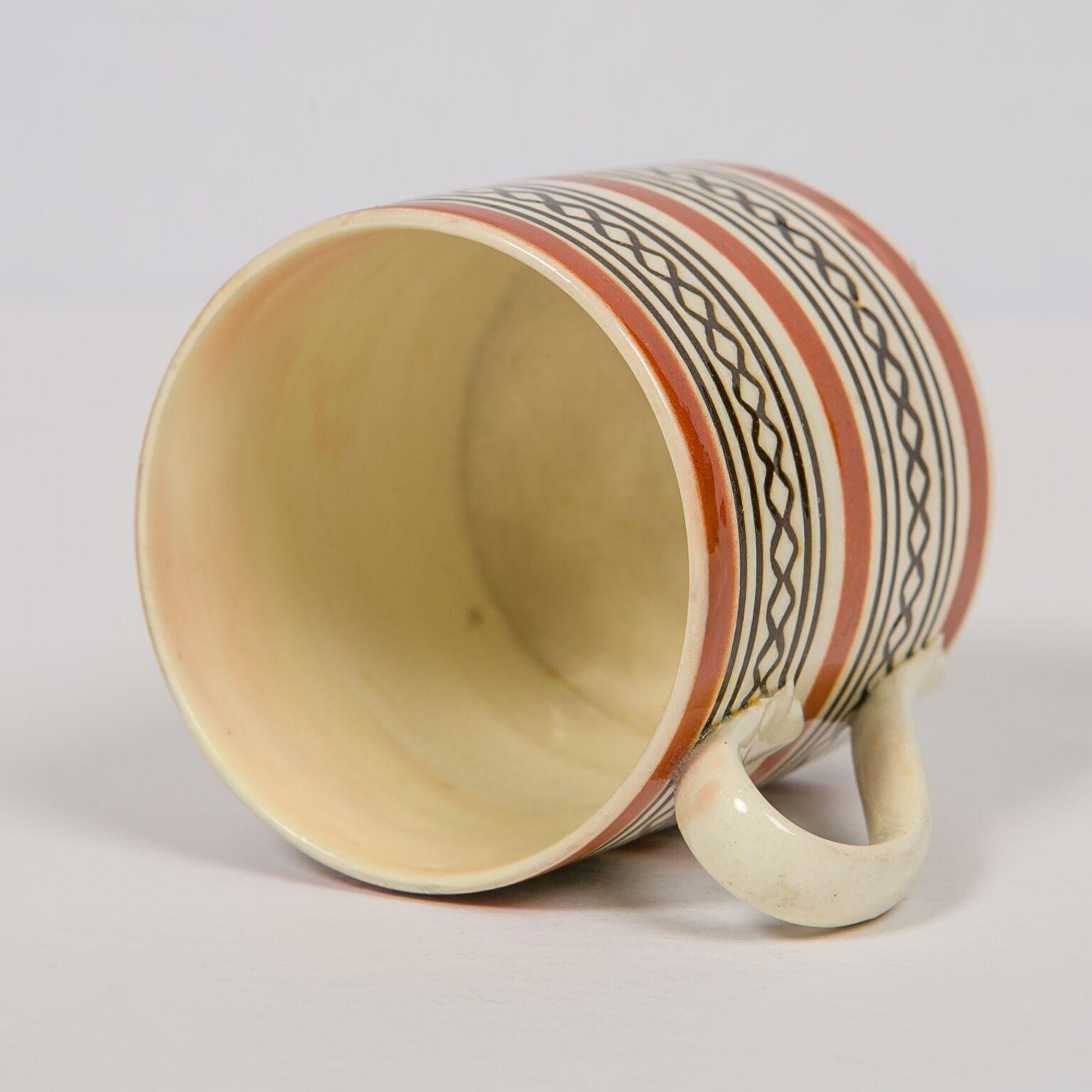 Small Mochaware mug made in England, circa 1820. Decorated with two bands of black engine-turned diamonds and bands of brown slip. The piece has a surprisingly modern look considering it was made 200 years ago. For more information on this type of