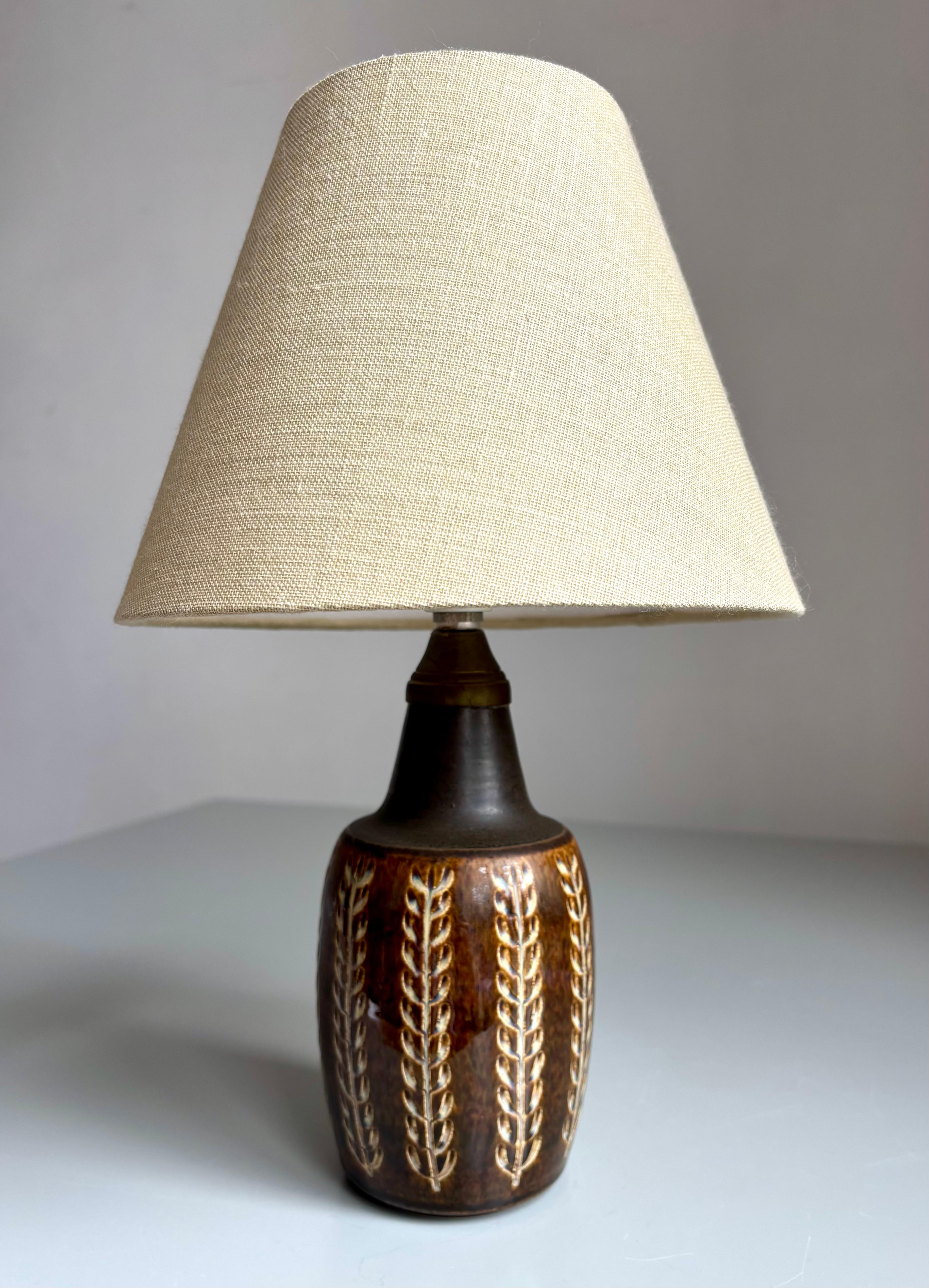 Small stoneware table lamp with stunning dark brown shiny glaze over hand-carved organic relief decor in vertical lines. Fitting for E14 bulb and switch on cord. Manufactured on the island of Bornholm by Søholm Stentøj in the 1960s.
Beautiful