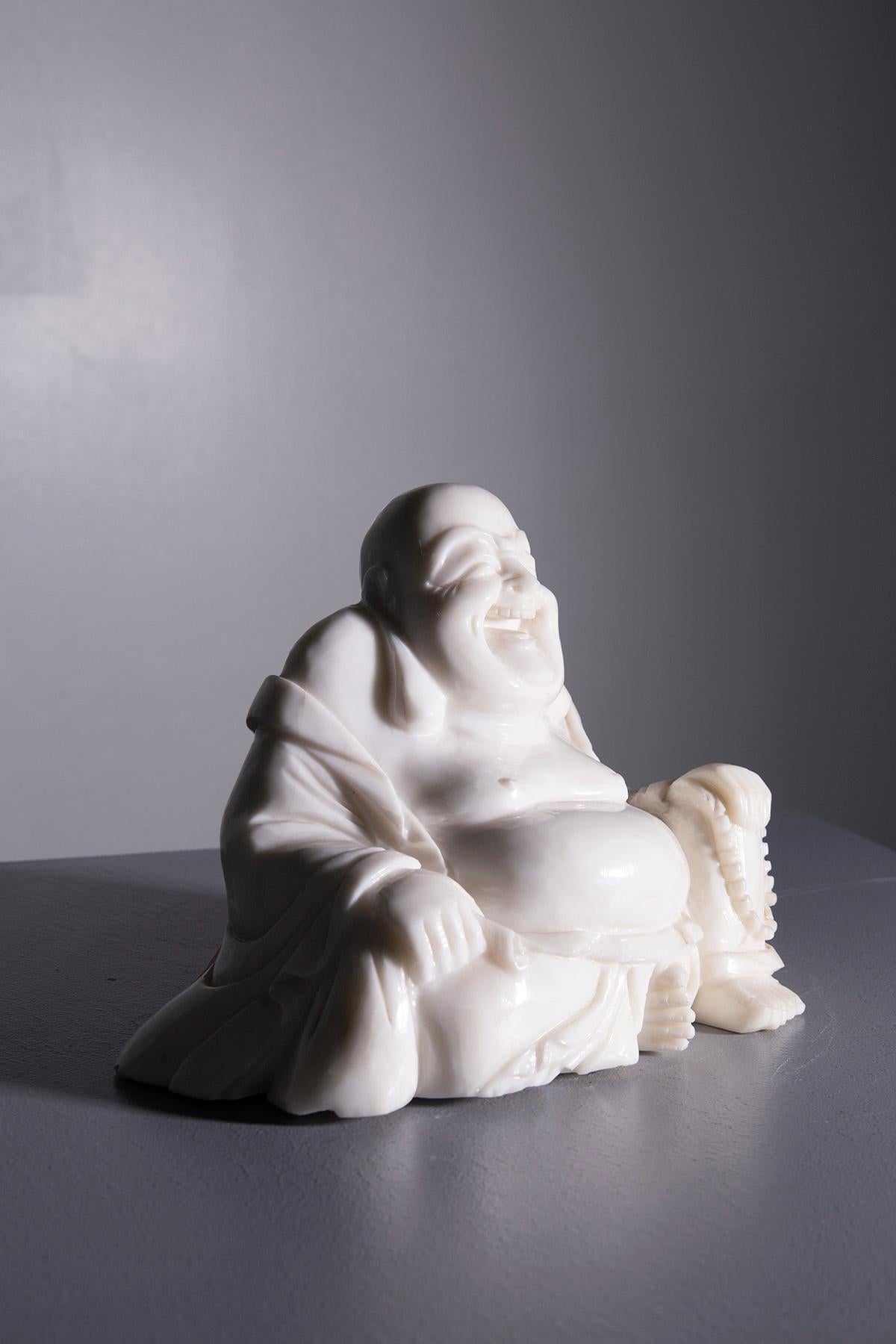 Cette sculpture en jade blanc poli représente le Bouddha Budai, également connu sous le nom de Bouddha rieur, dans une posture rayonnante de joie et de sérénité. La finition brillante du jade blanc confère à la statue une aura lumineuse, presque